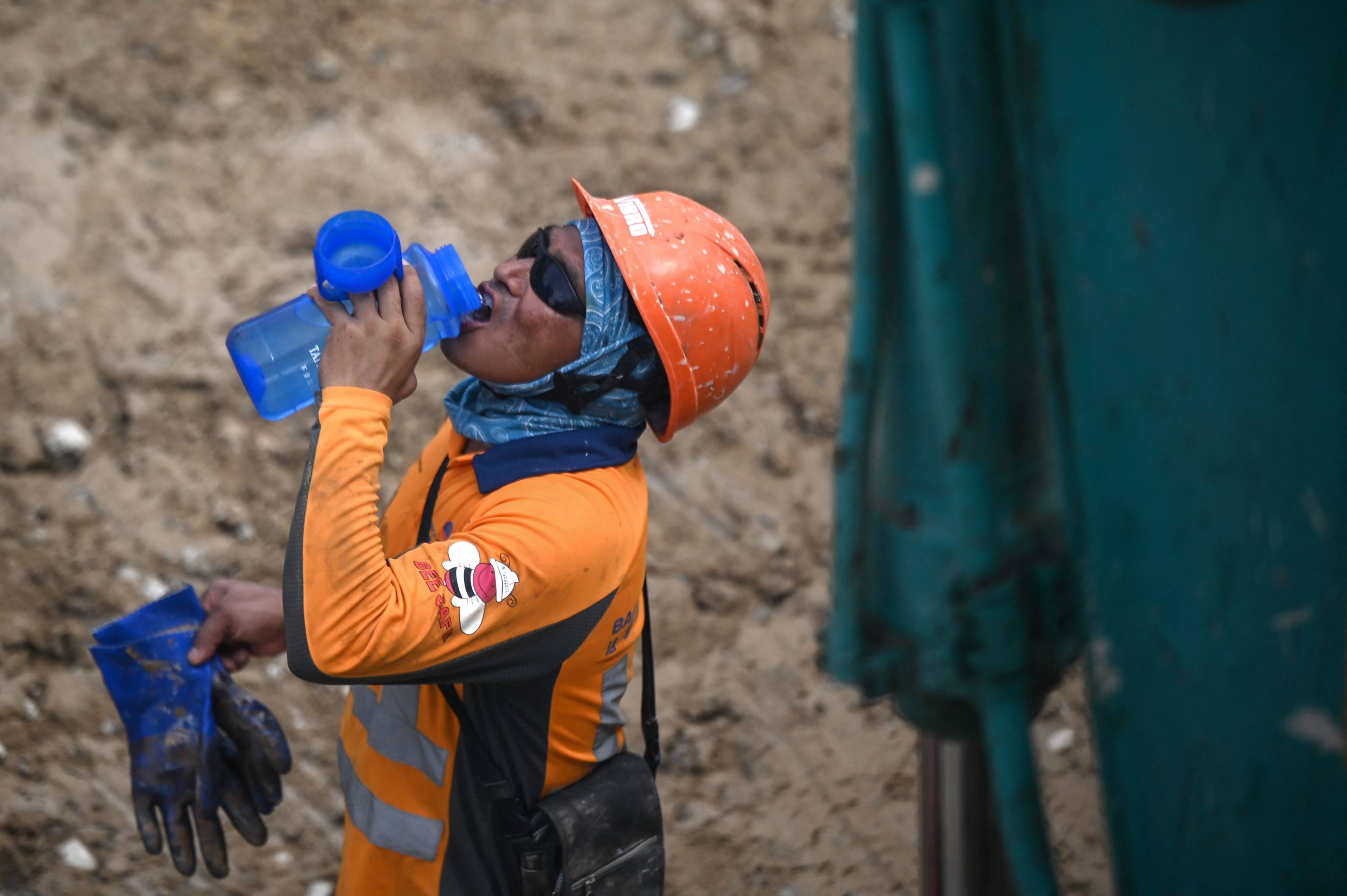 A construction worker drinks water during hot weather in Hong Kong. AXA has launched a heat-related insurance policy in the city. Photo: AFP