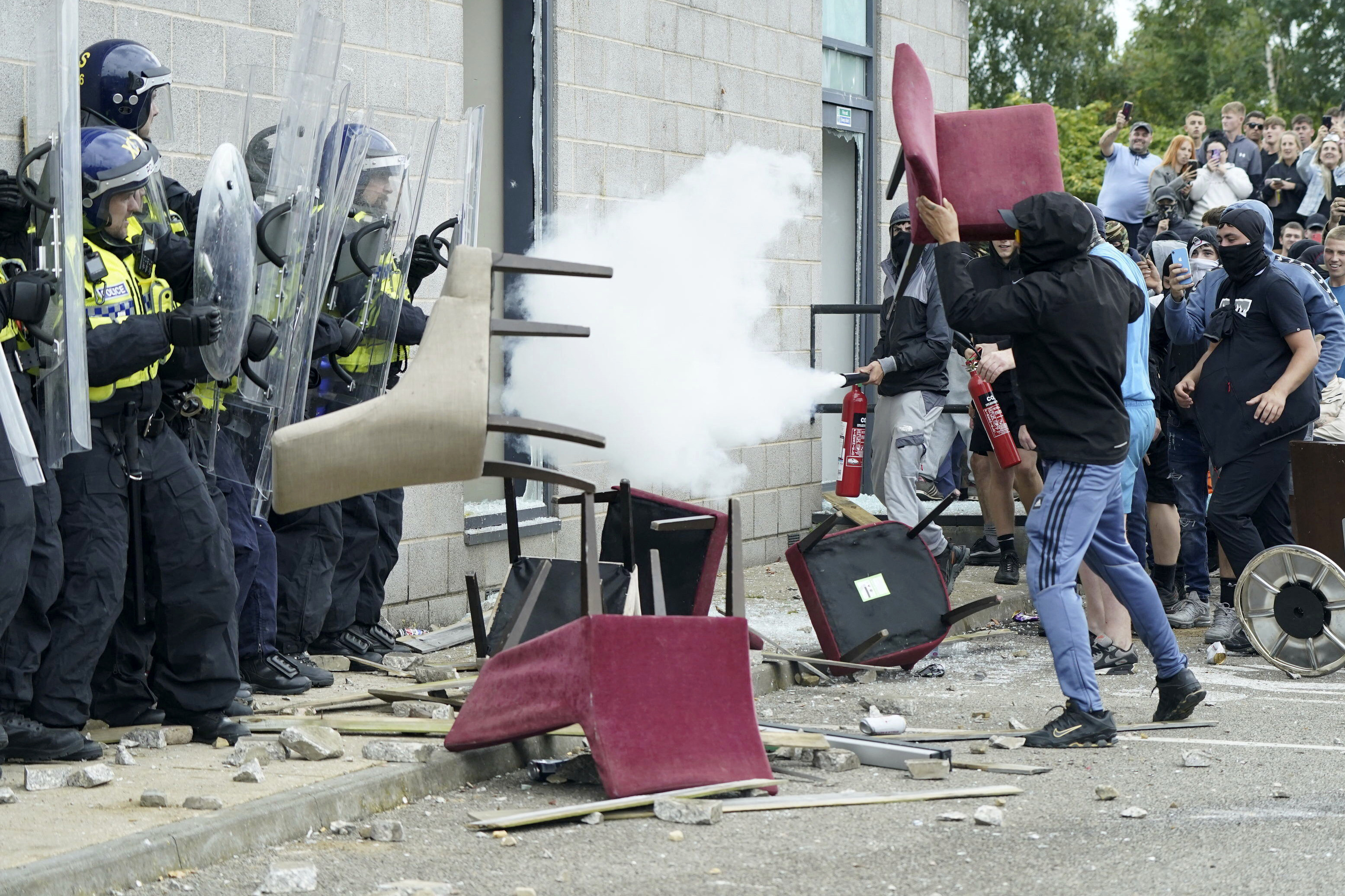 A rioter throws a chair at police officers during an anti-immigration protest outside the Holiday Inn Express in Rotherham, England, on August 4. Photo: AP