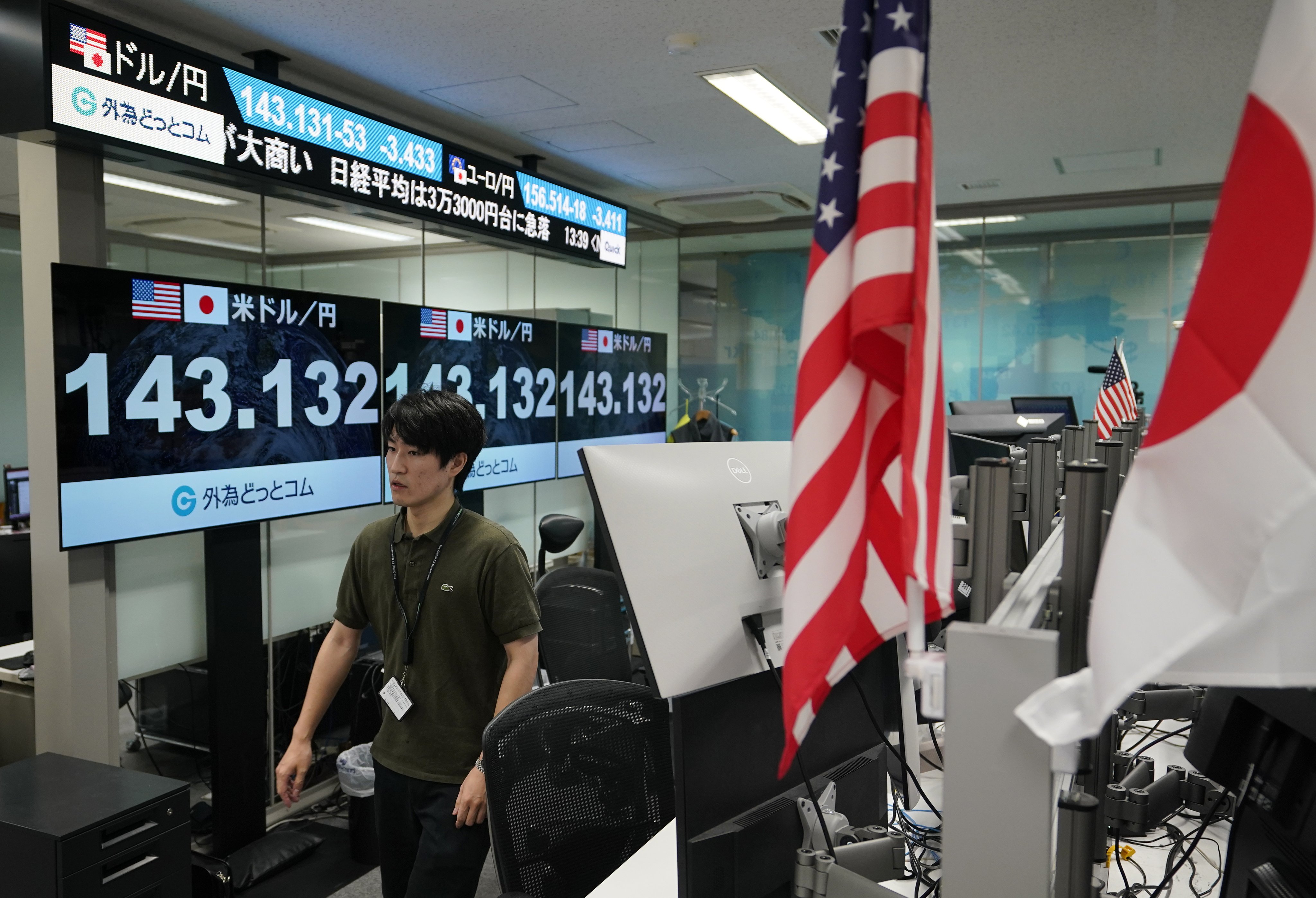 A dealer walks next to monitors showing the foreign exchange rate between the Japanese yen and US dollar in Tokyo. Photo: EPA-EFE