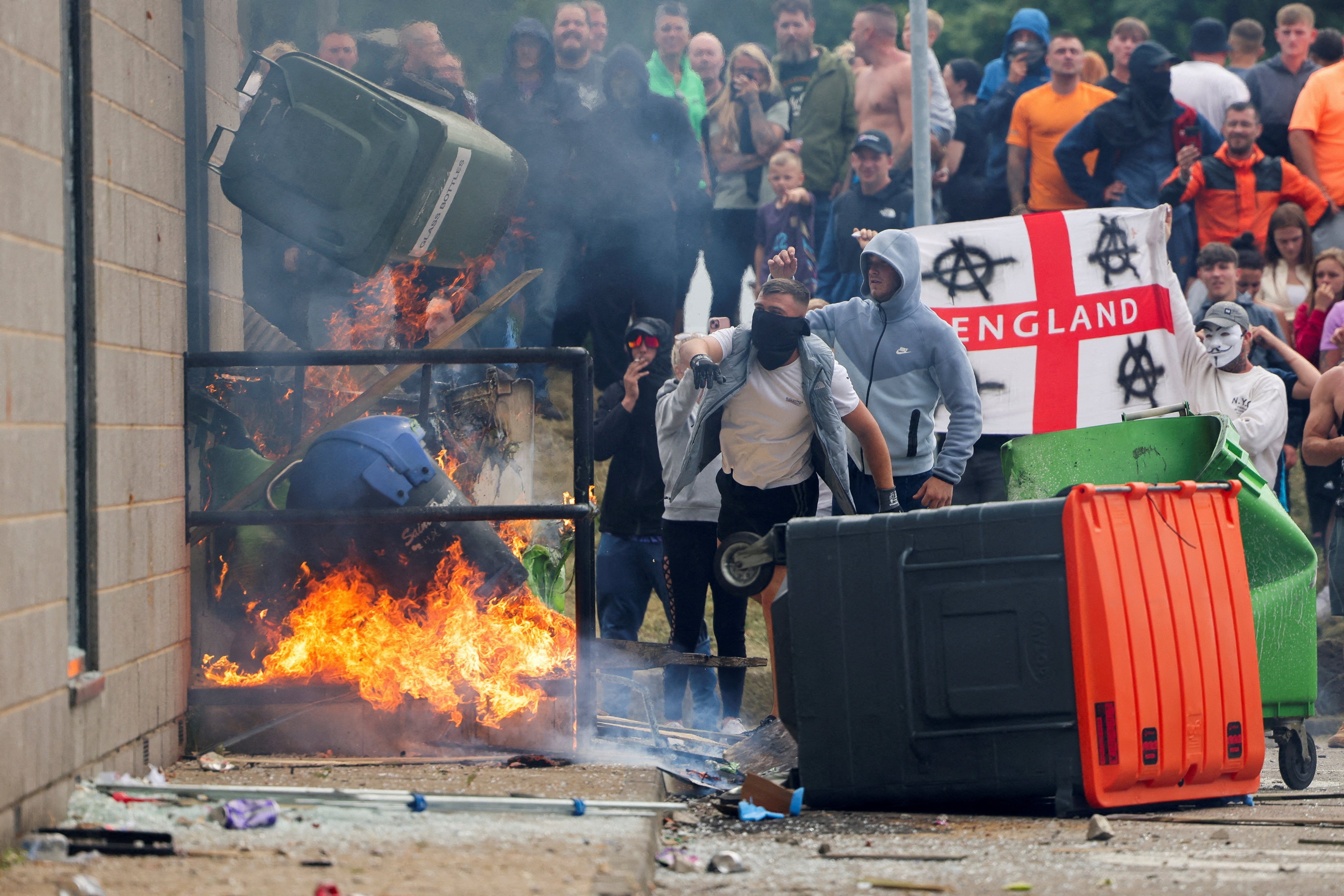 Protestors throw a garbage bin on fire outside a hotel in Rotherham, Britain. Photo: Reuters