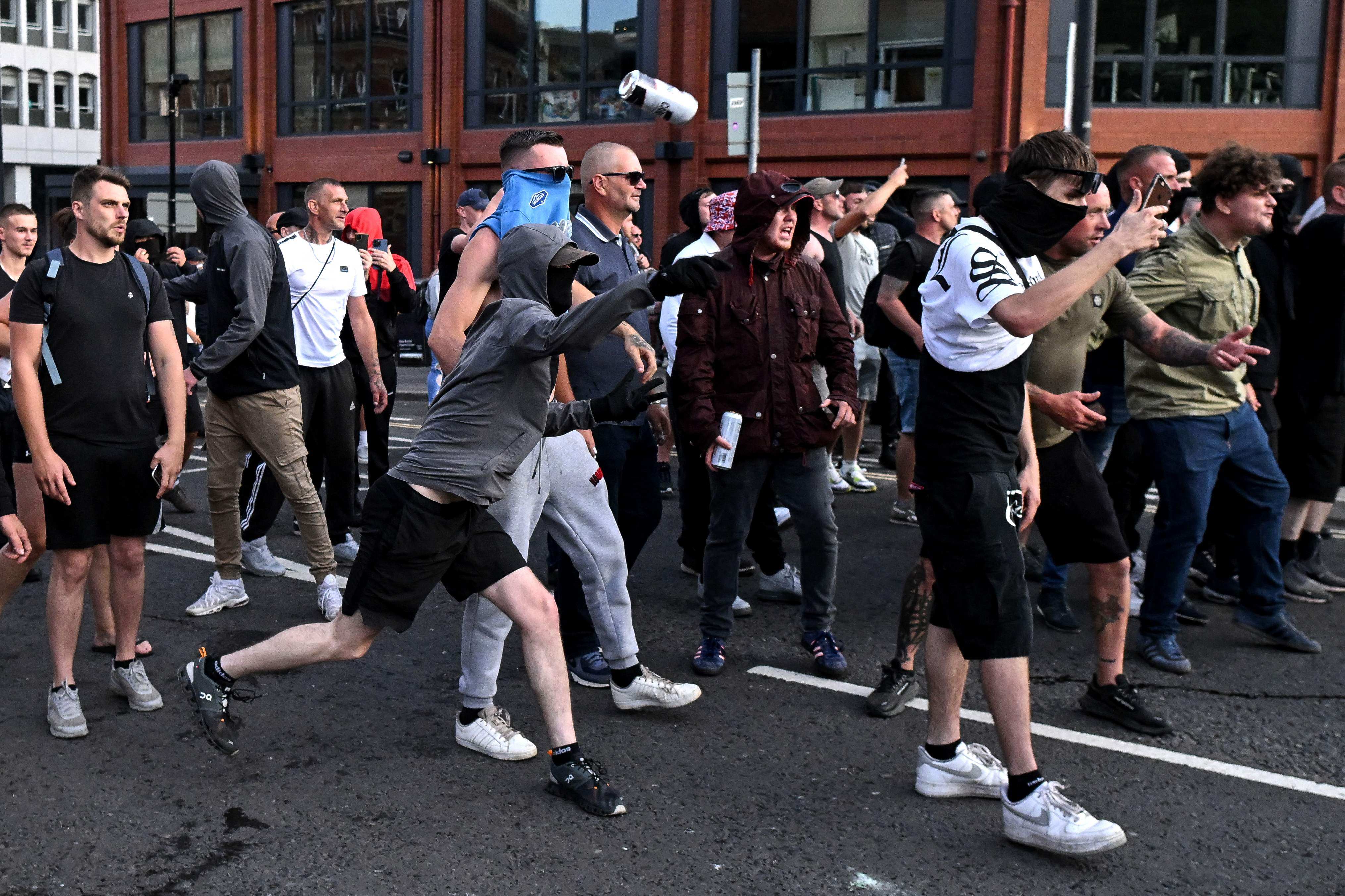 A masked protester throws a can of beer towards riot police in Bristol, southern England, on August 3. Photo: AFP