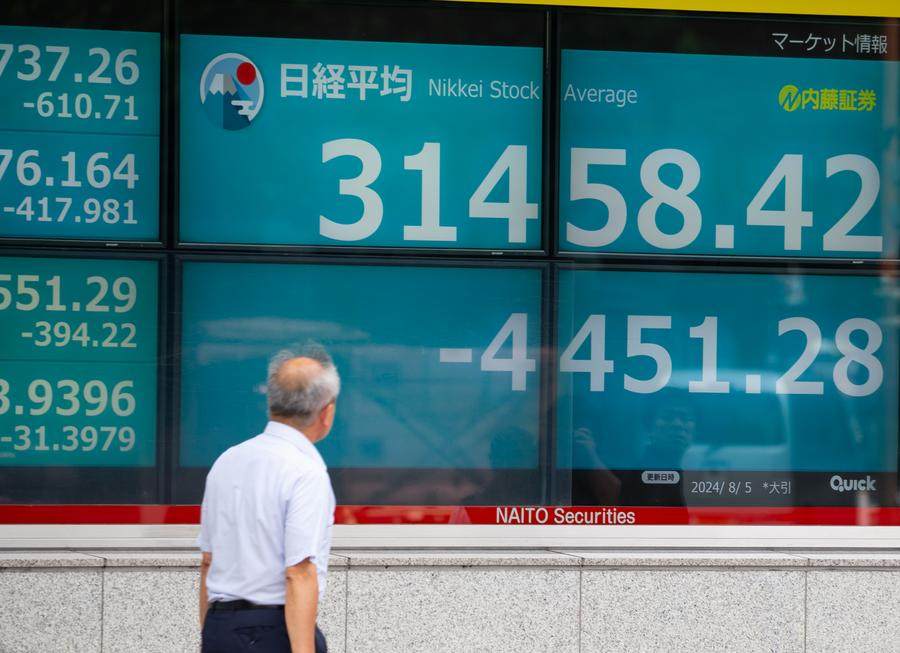 A pedestrian passes a screen showing real-time stock market information in Tokyo, Japan, on August 5.  Photo: Xinhua