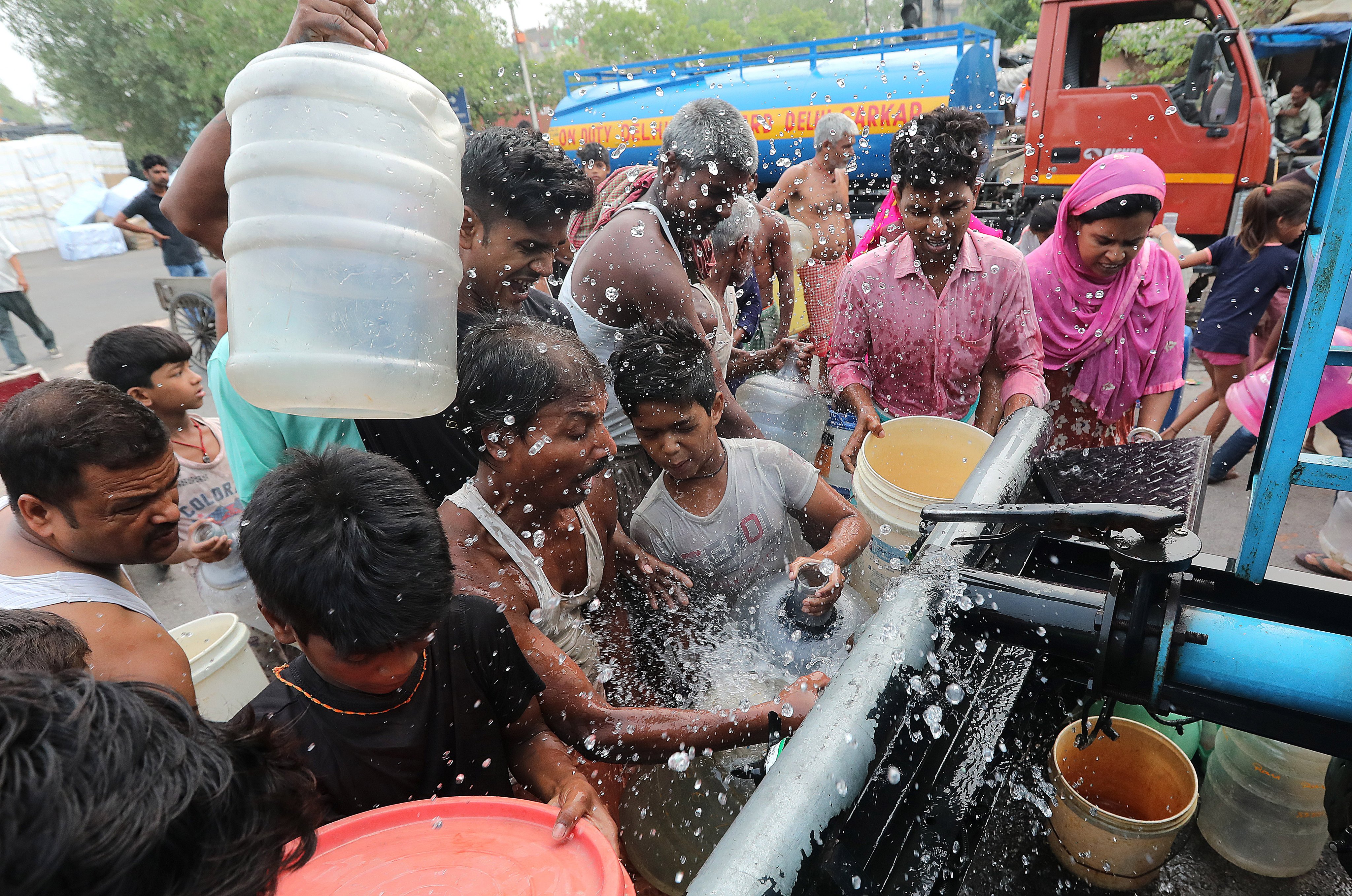 People rush to fill water canisters at a Delhi Jal Board tanker in a makeshift settlement in Geeta Colony, New Delhi, on June 26. Photo: EPA-EFE