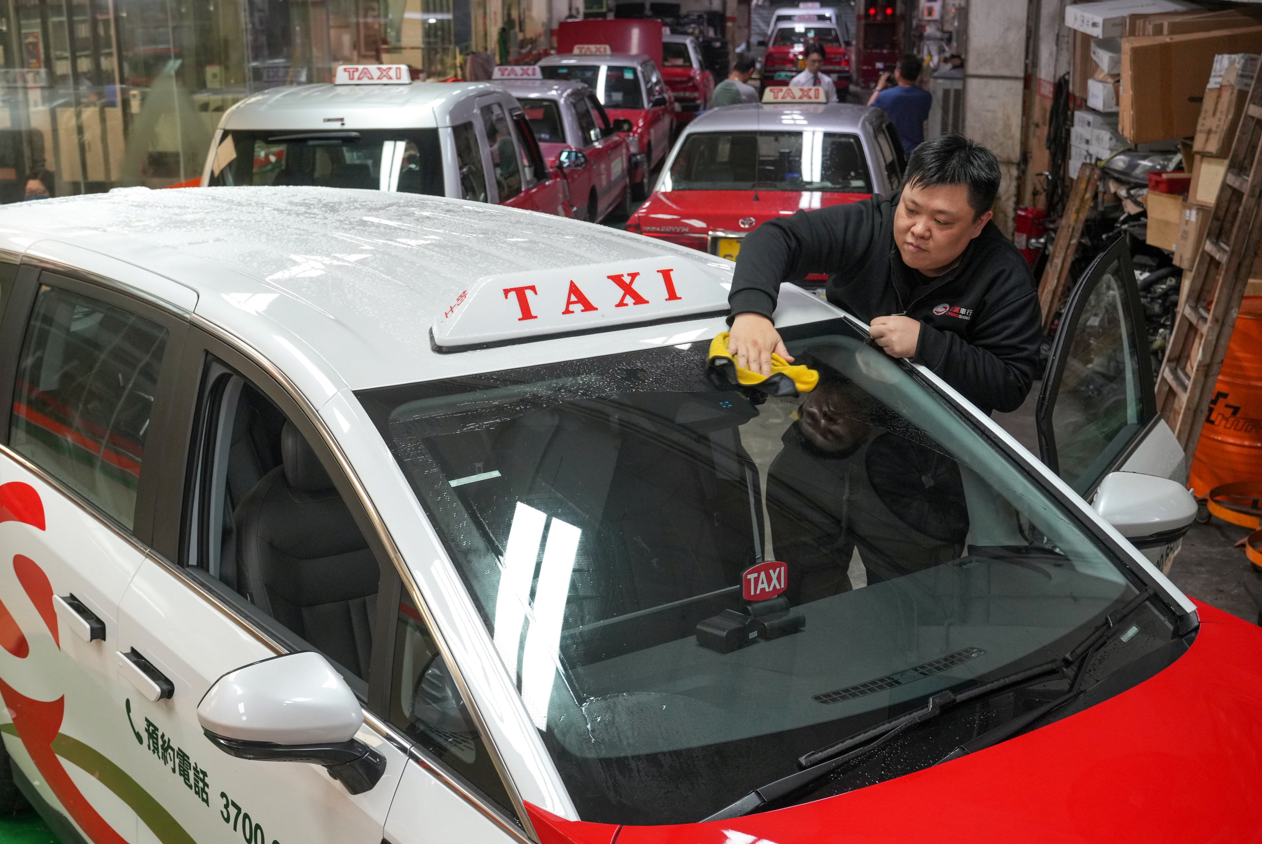 An employee of a taxi service cleans one of the company’s newest cars in To Kwa Wan on July 31. Hong Kong’s taxi licencing scheme will not allocate extra resources, but rather reshuffle those the city already has. Photo: May Tse