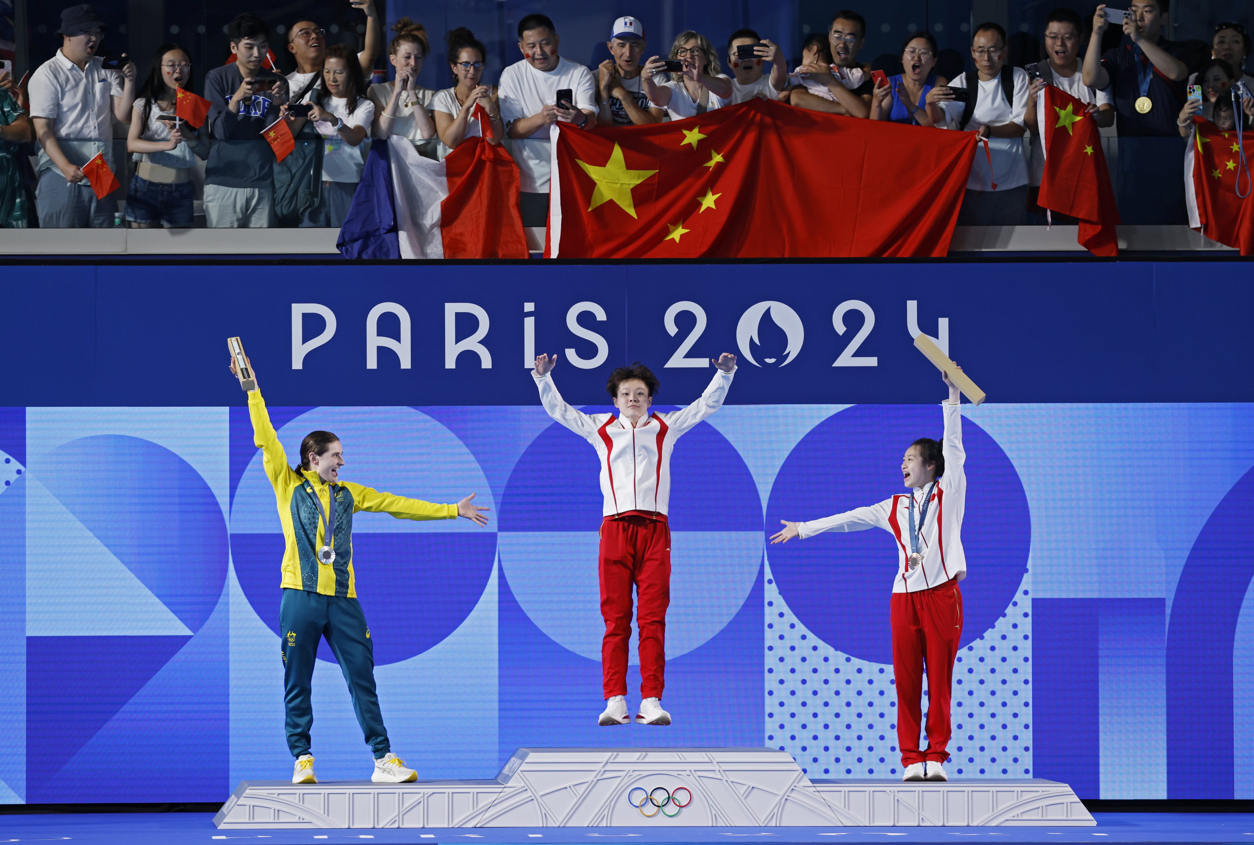 Chen Yiwen is hailed by fellow Chinese Chang Yani (right) and silver medallist Maddison Keeney (left), as she leaps onto the top of the podium at Paris Aquatics Centre. Photo: EPA.