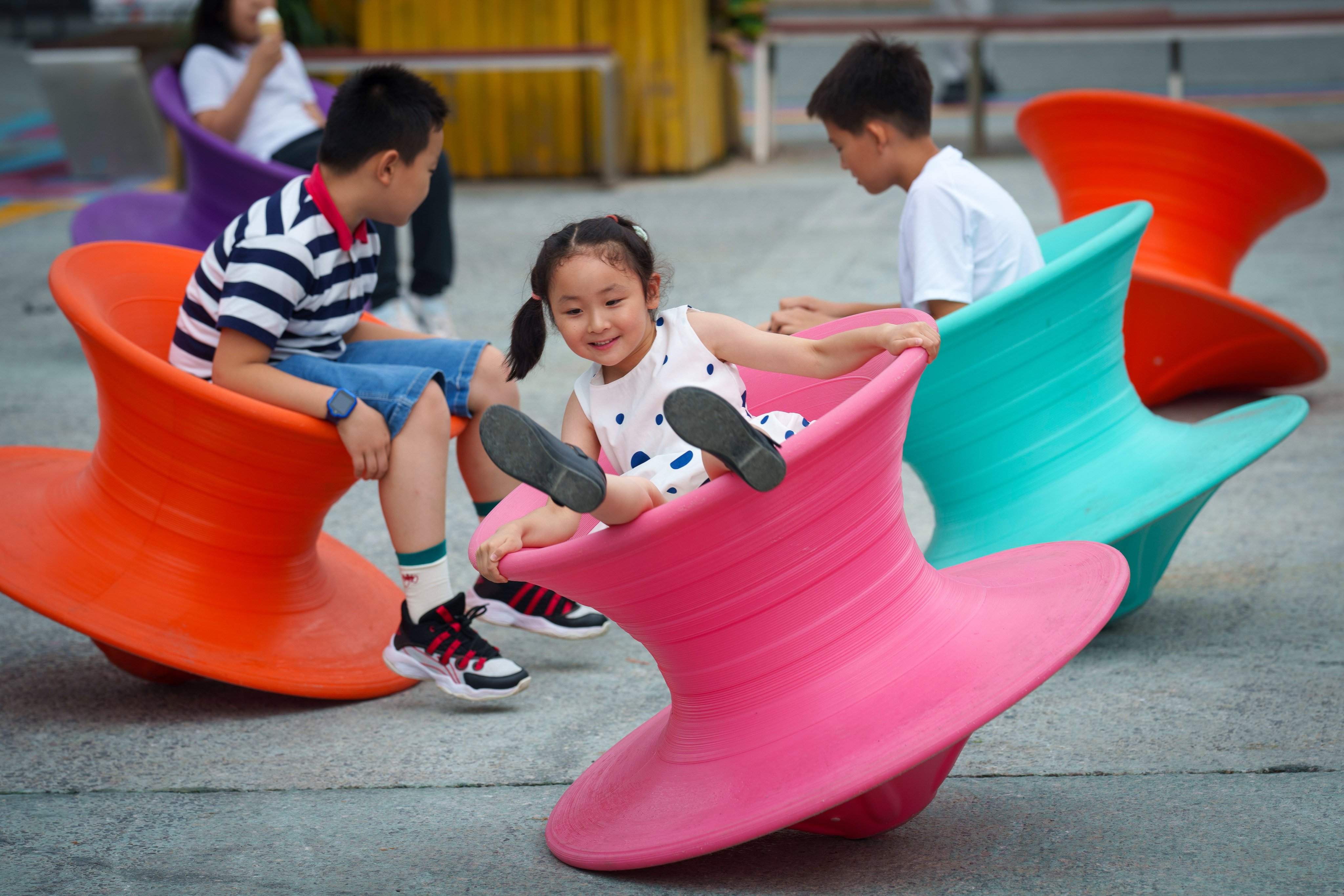 Children play with spinning chairs at a shopping mall in Beijing. China is one of 63 countries and areas with declining populations. Photo: AP 