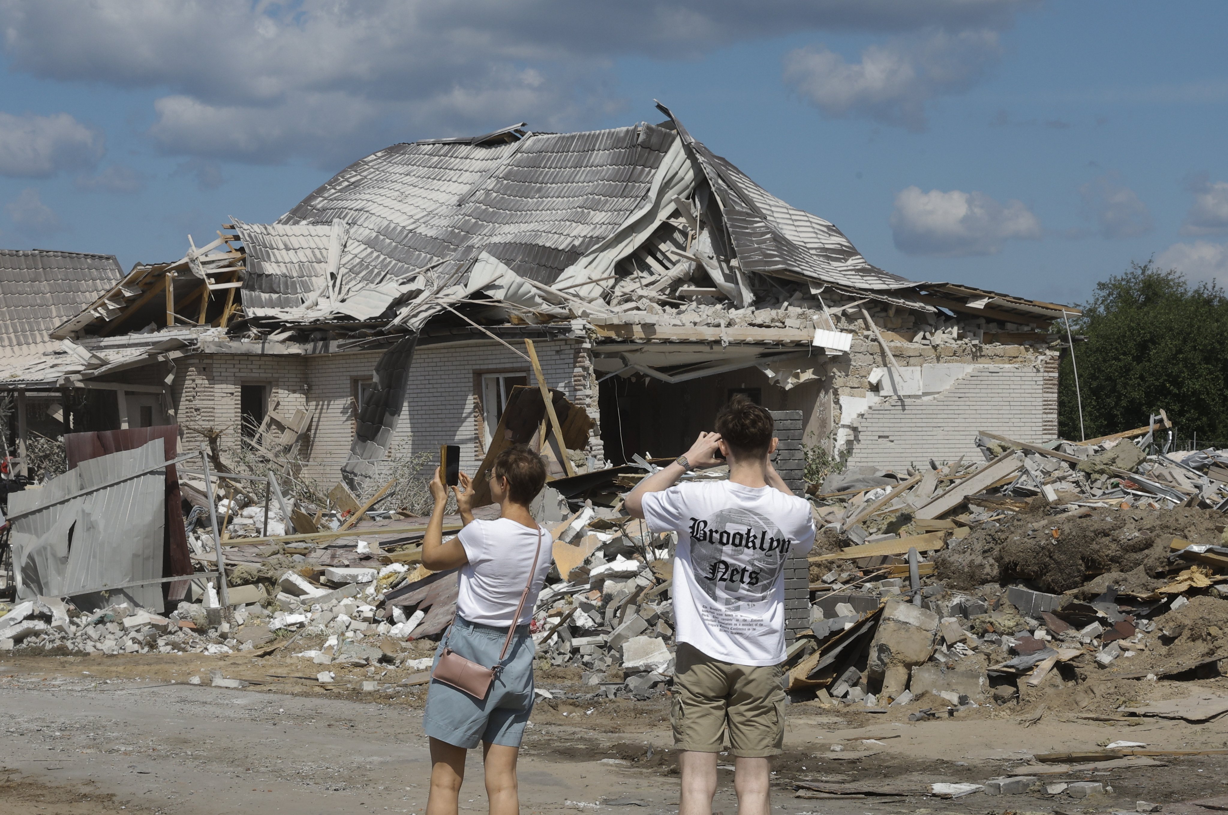 Locals take photographs in a village in the Kyiv region of Ukraine on Sunday following a Russia attack. Photo: EPA-EFE