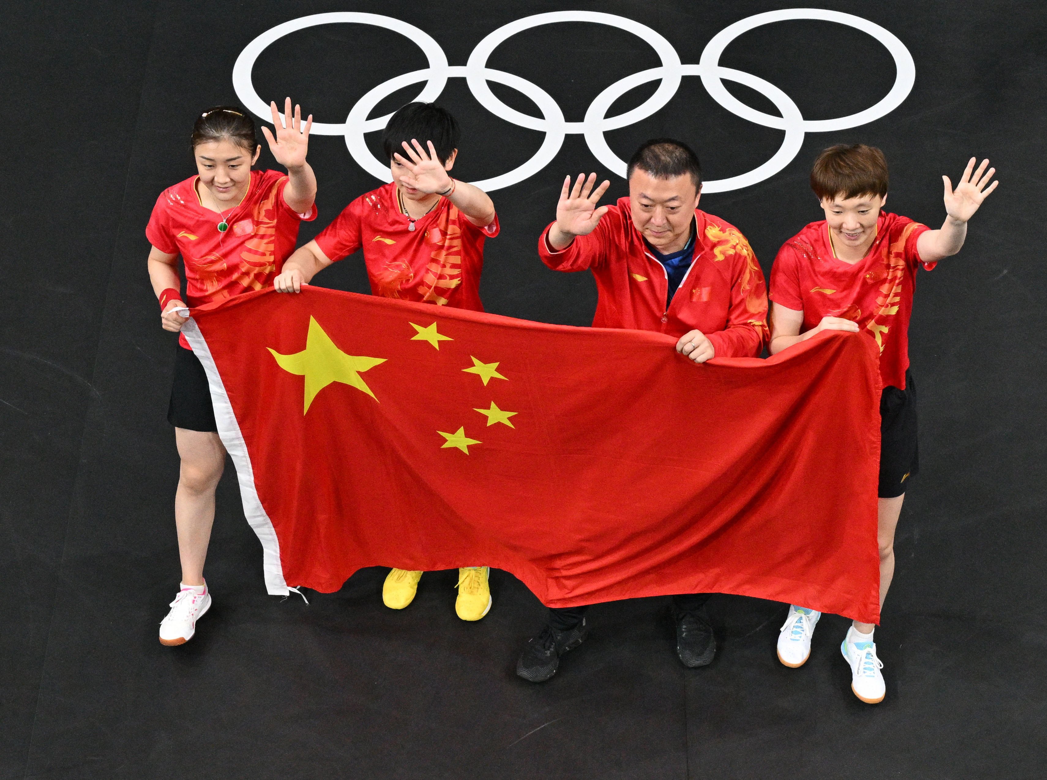 The China team and their coach wave to supporters after winning the women’s team table tennis gold. Photo: Reuters