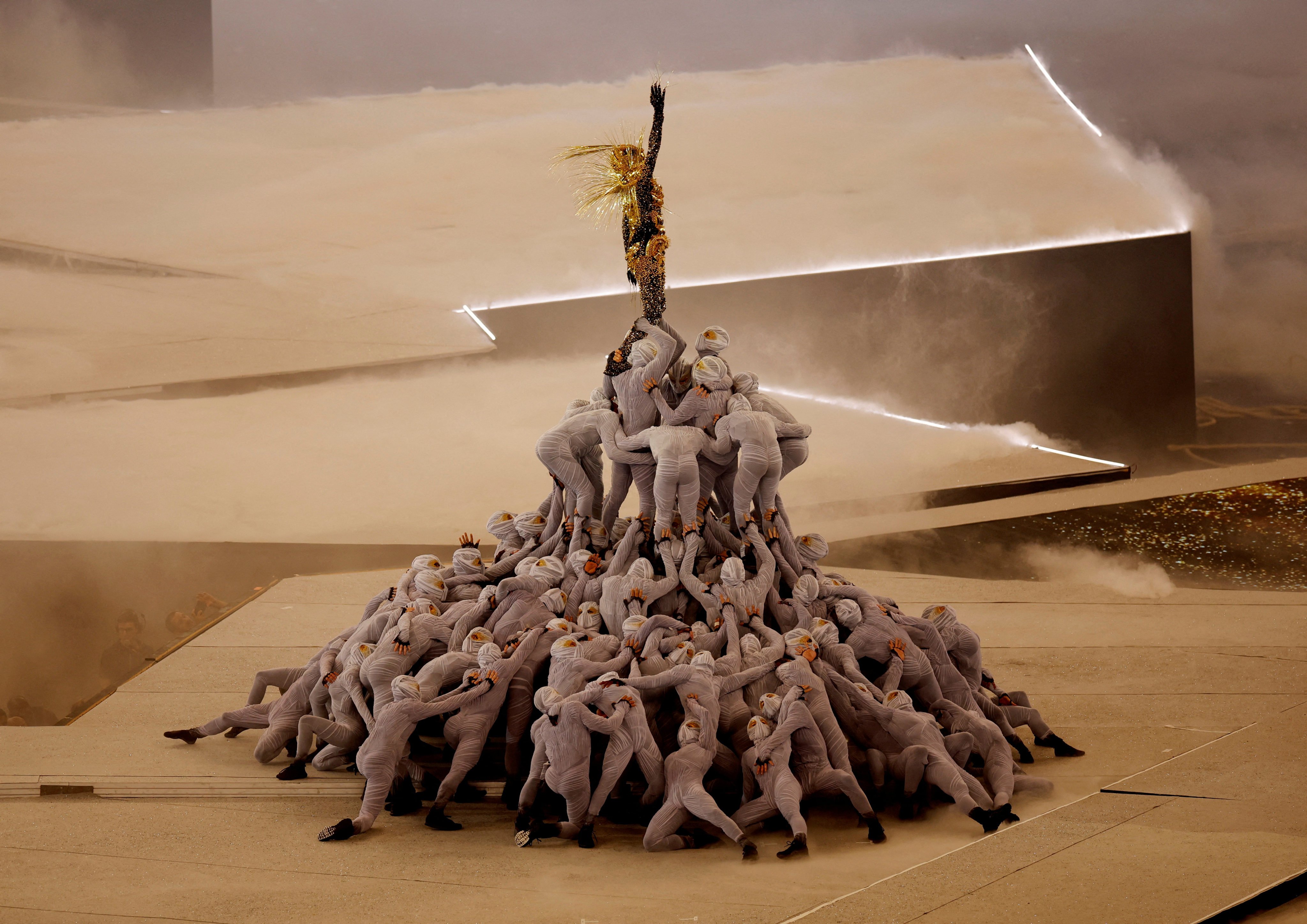 The Golden Voyager stands atop a pile of masked dancers in a performance during the closing ceremony. Photo: Reuters