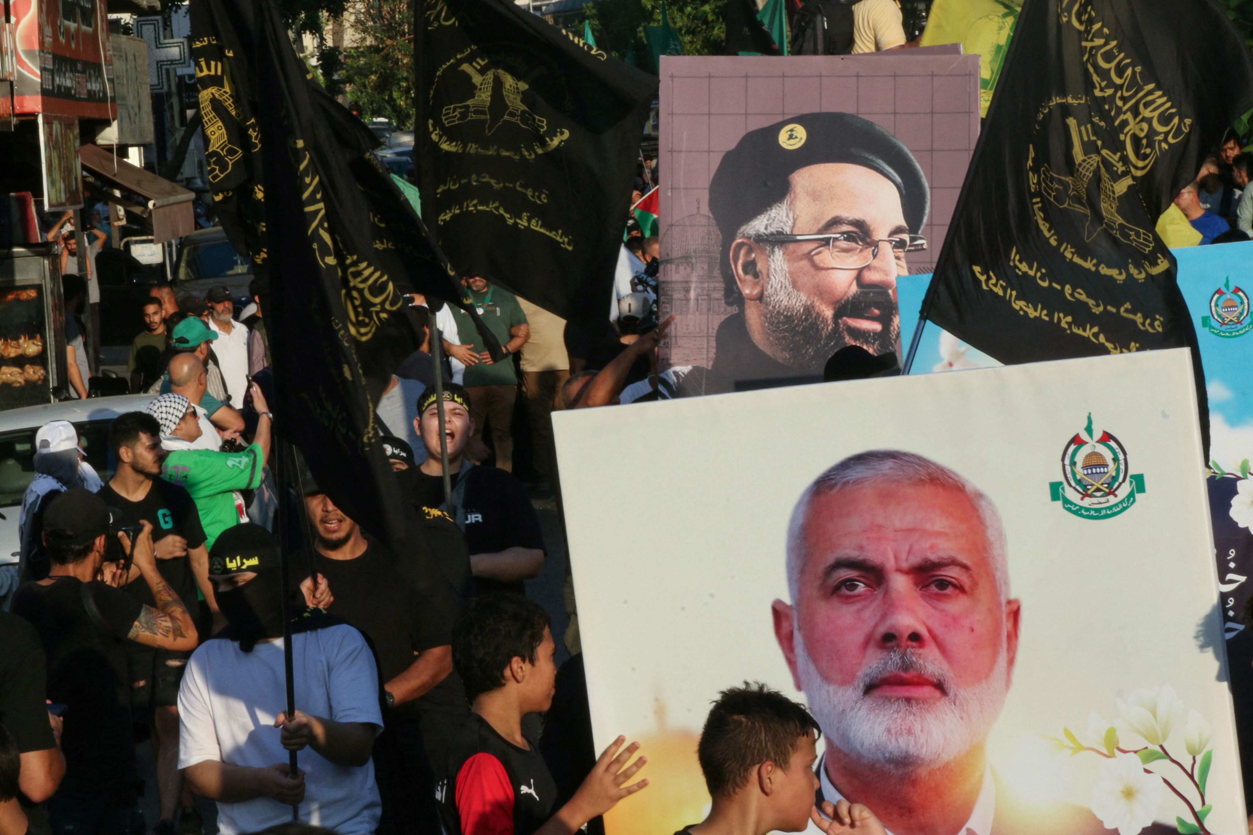 People march in Saida, Lebanon, to protest the assassinations of Hamas leader Ismail Haniyeh (portrait bottom) and Hezbollah military commander Fuad Shukur (portrait top), on August 5. Photo: AFP 