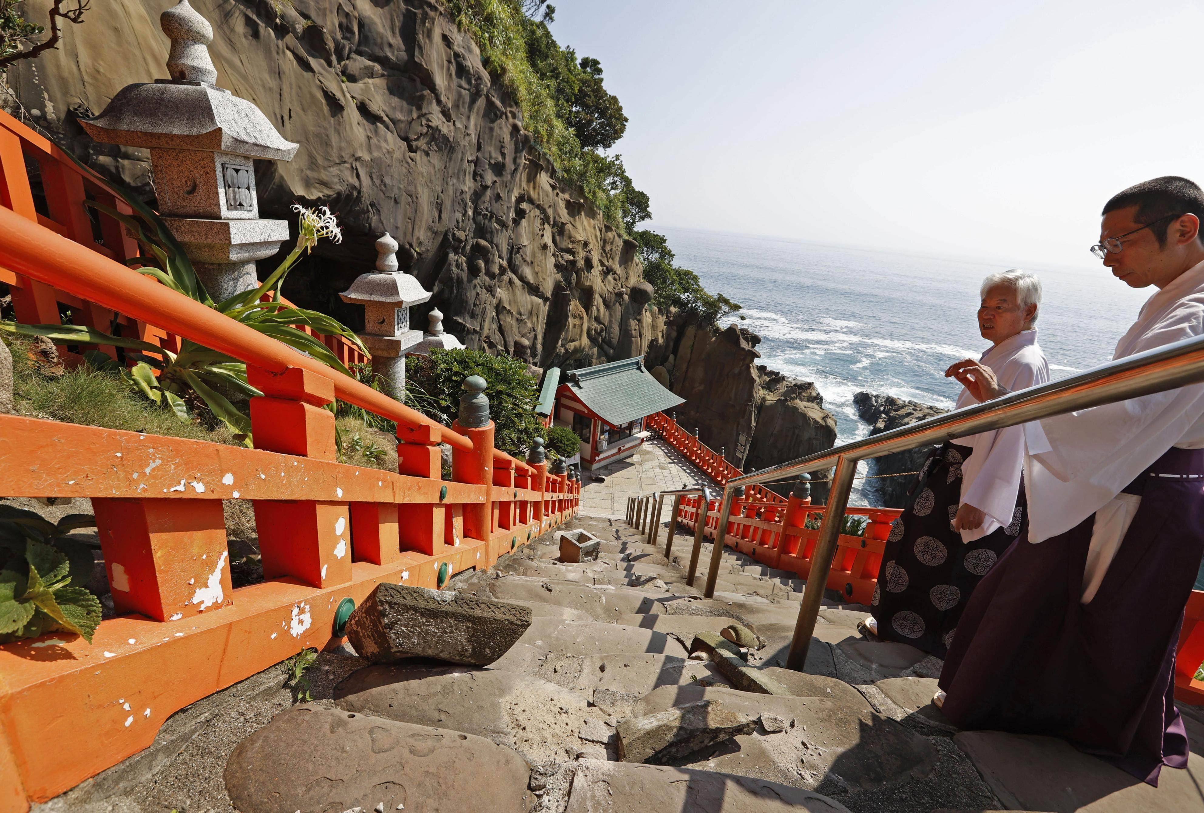 Quake-damaged stone lanterns are examined at Udo Jingu shrine in Miyazaki prefecture. Photo: Kyodo