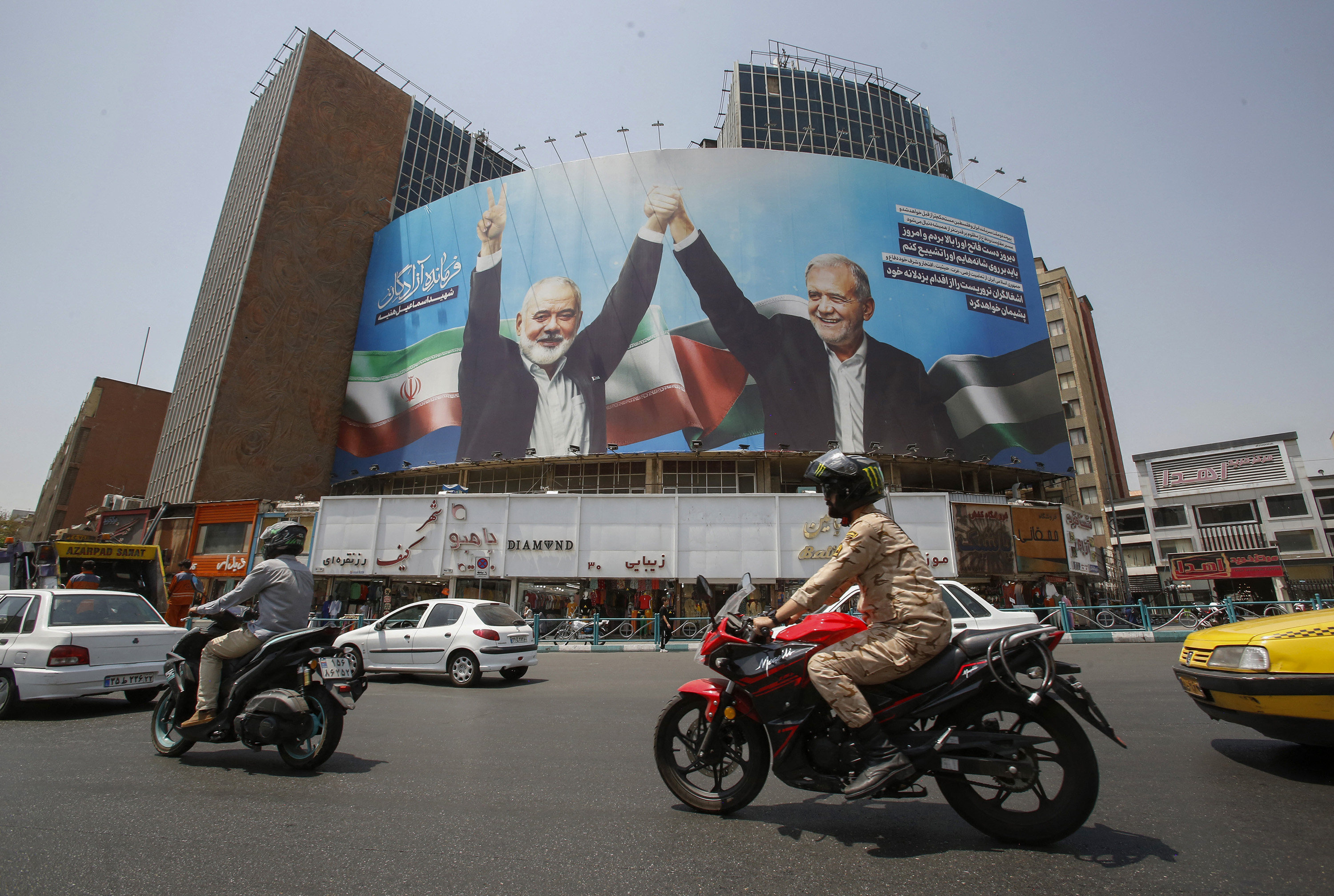 Vehicles drive past a billboard depicting slain leader of the Palestinian Hamas group Ismail Haniyeh (left) in Tehran on August 8. Photo: AFP/Getty Images/TNS