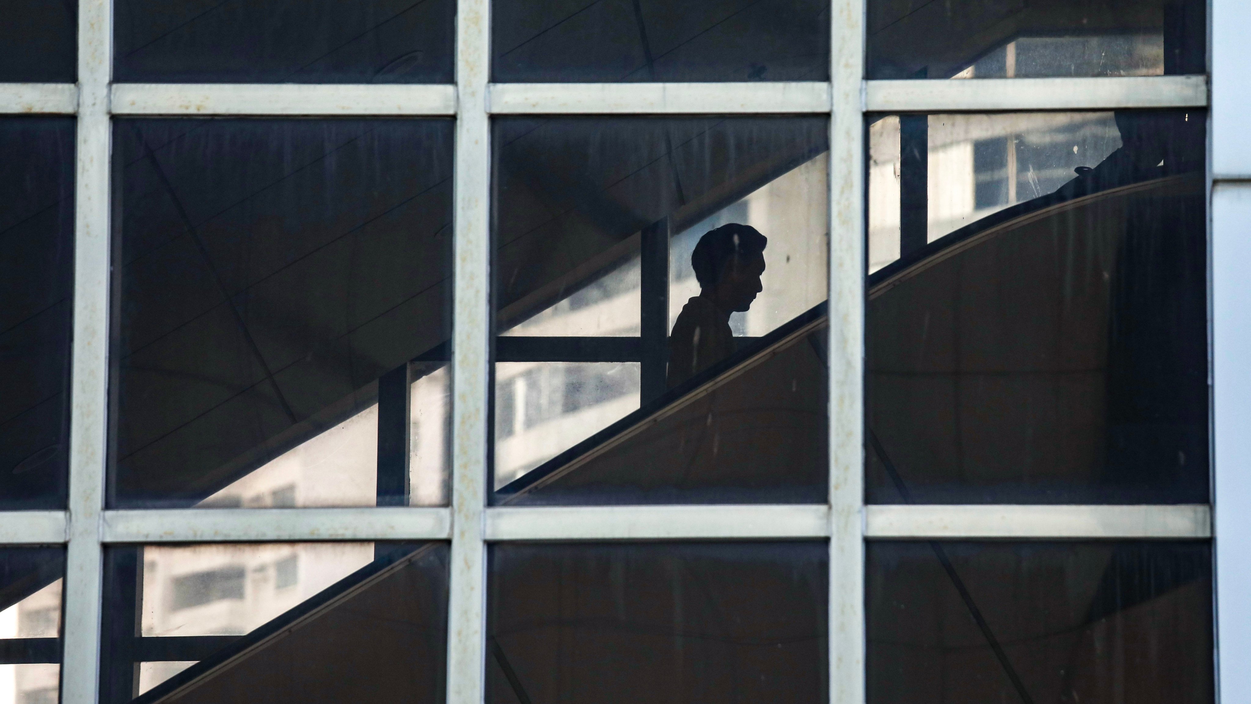 A person riding an escalator is reflected in the glass of an office building in Admiralty on October 17, 2023. Photo: Xiaomei Chen