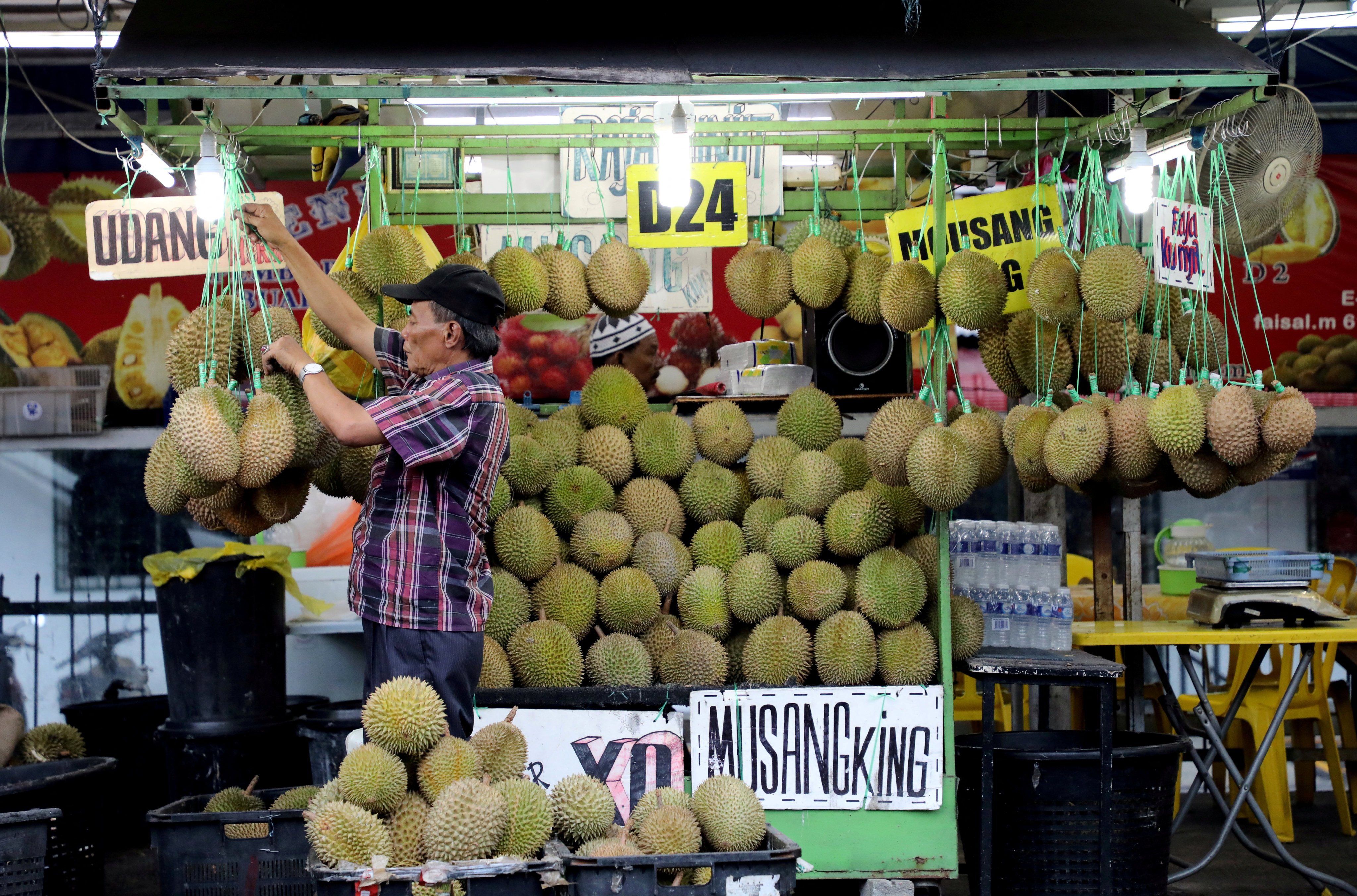 A man arranges durians at a stall in Kuala Lumpur. China’s reforms are expected to stimulate economic growth, and stronger economic performance in China typically results in higher demand for Malaysian exports. Photo: Reuters 