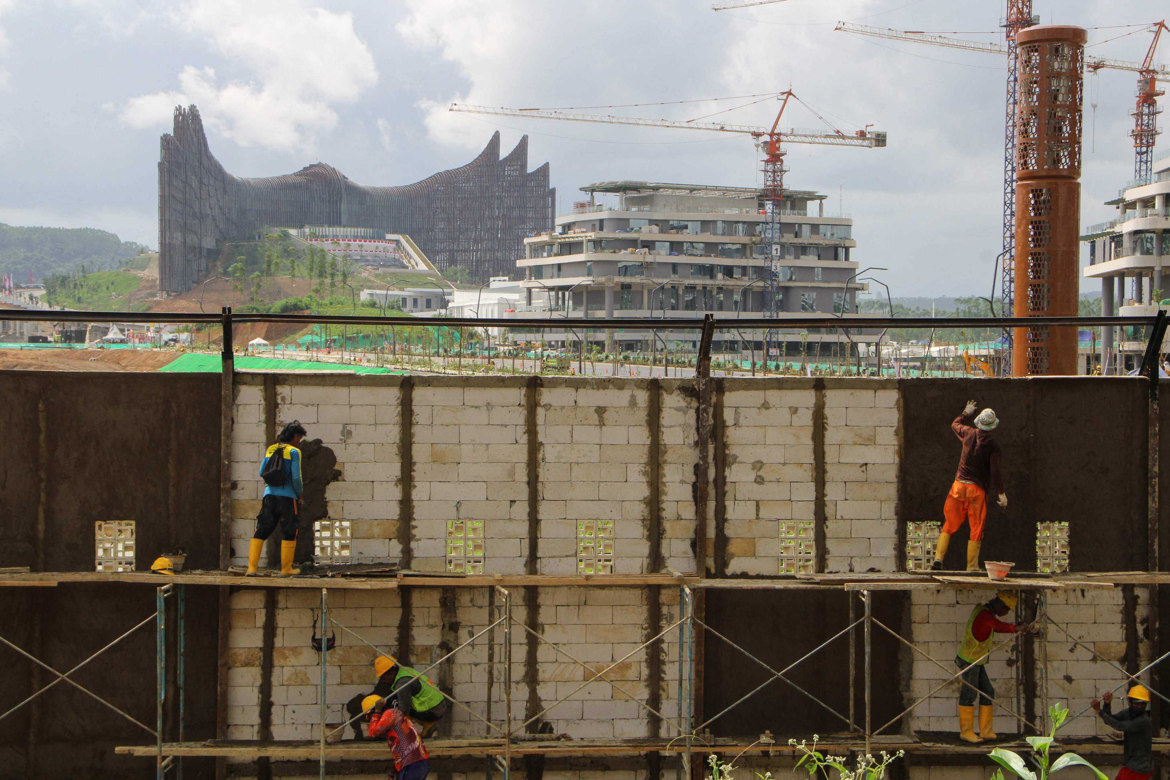 Workers build a wall in Nusantara on August 10 with the future presidential palace under construction in the background. Photo: AFP