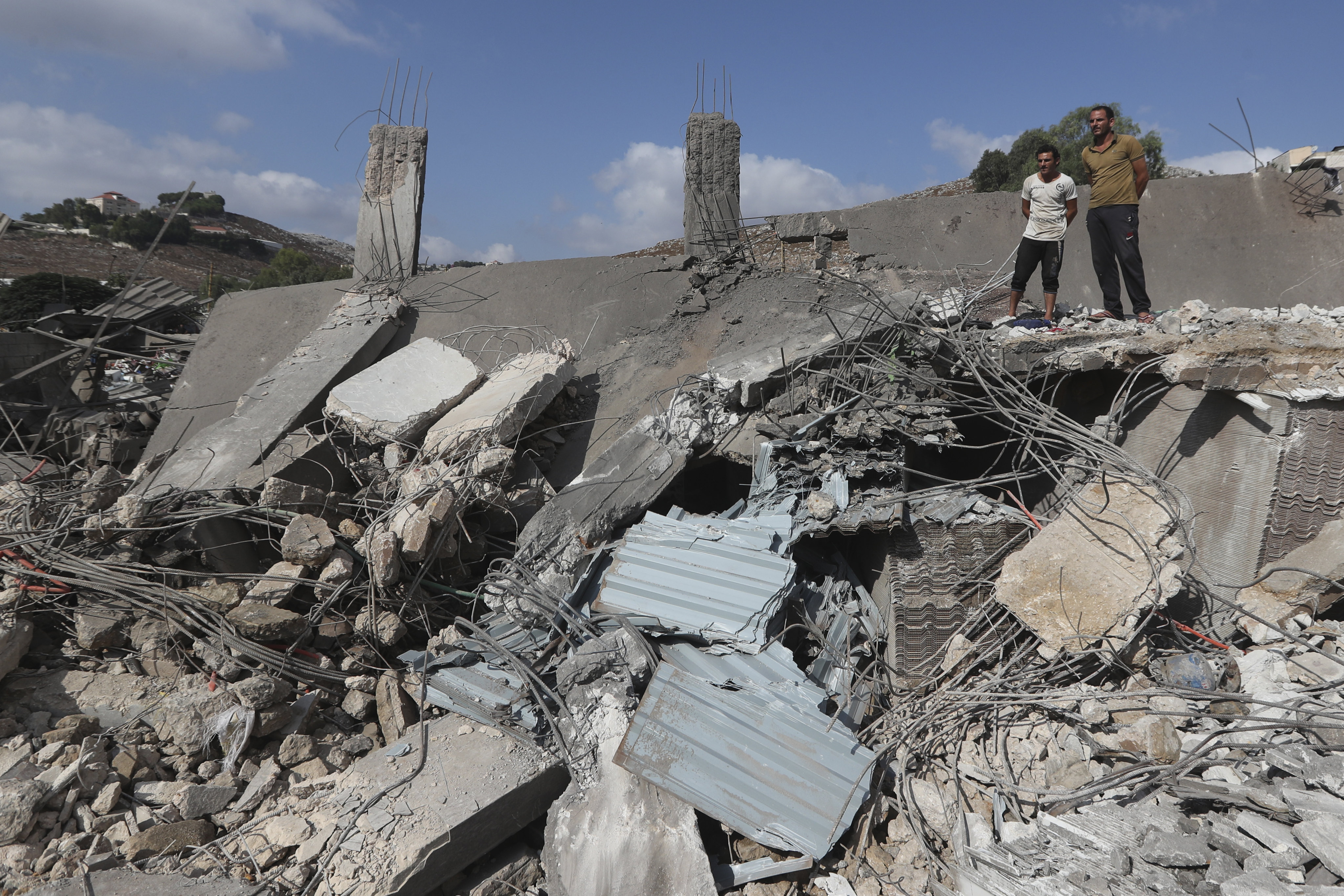 Civilians watch an industrial area destroyed by an Israeli airstrike, in south Lebanon on Saturday. Photo: AP