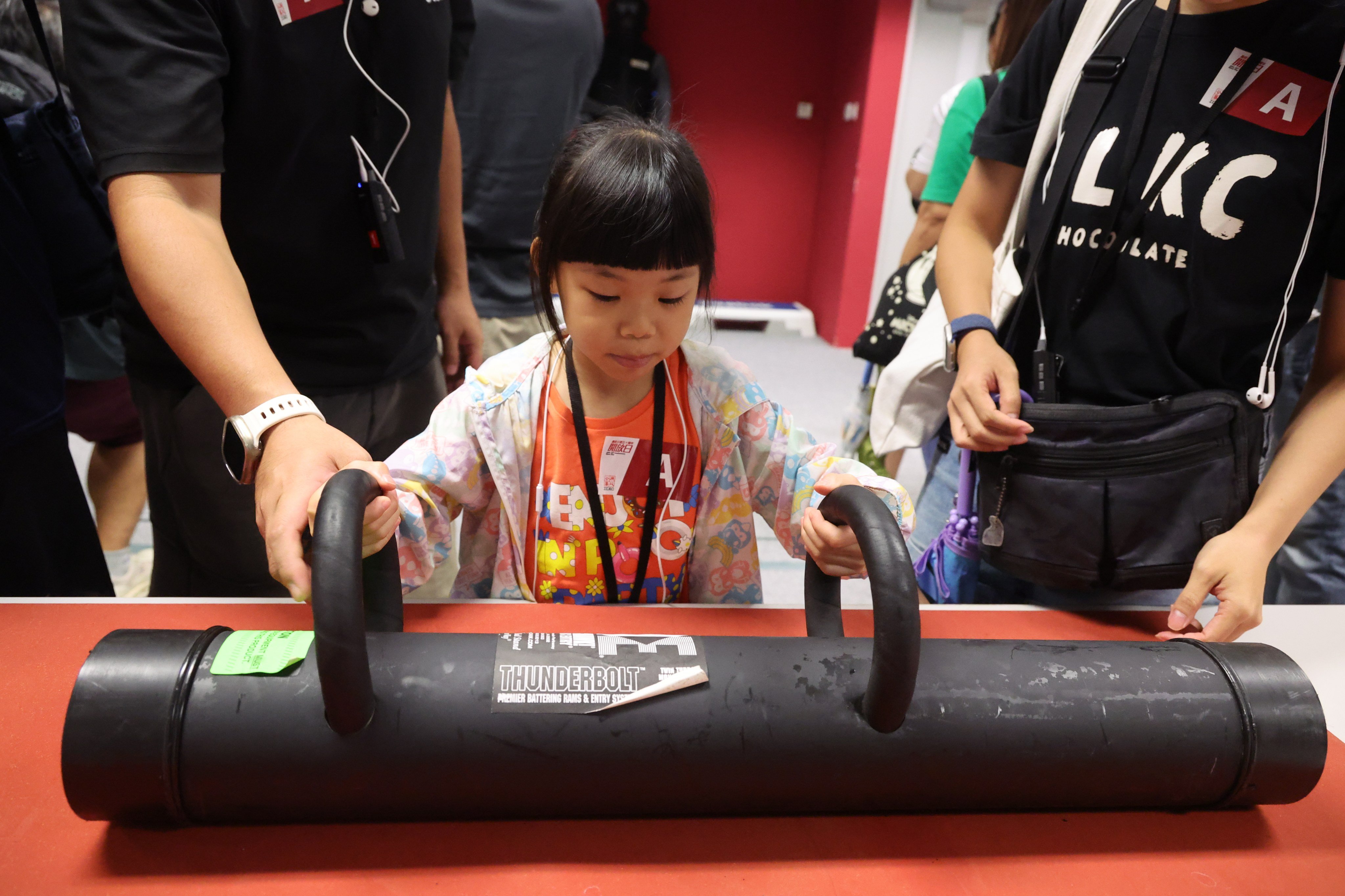 A young girl gets to grips with a battering ram on display at the ICAC’s weapons facility during an open day. Photo: Dickson Lee