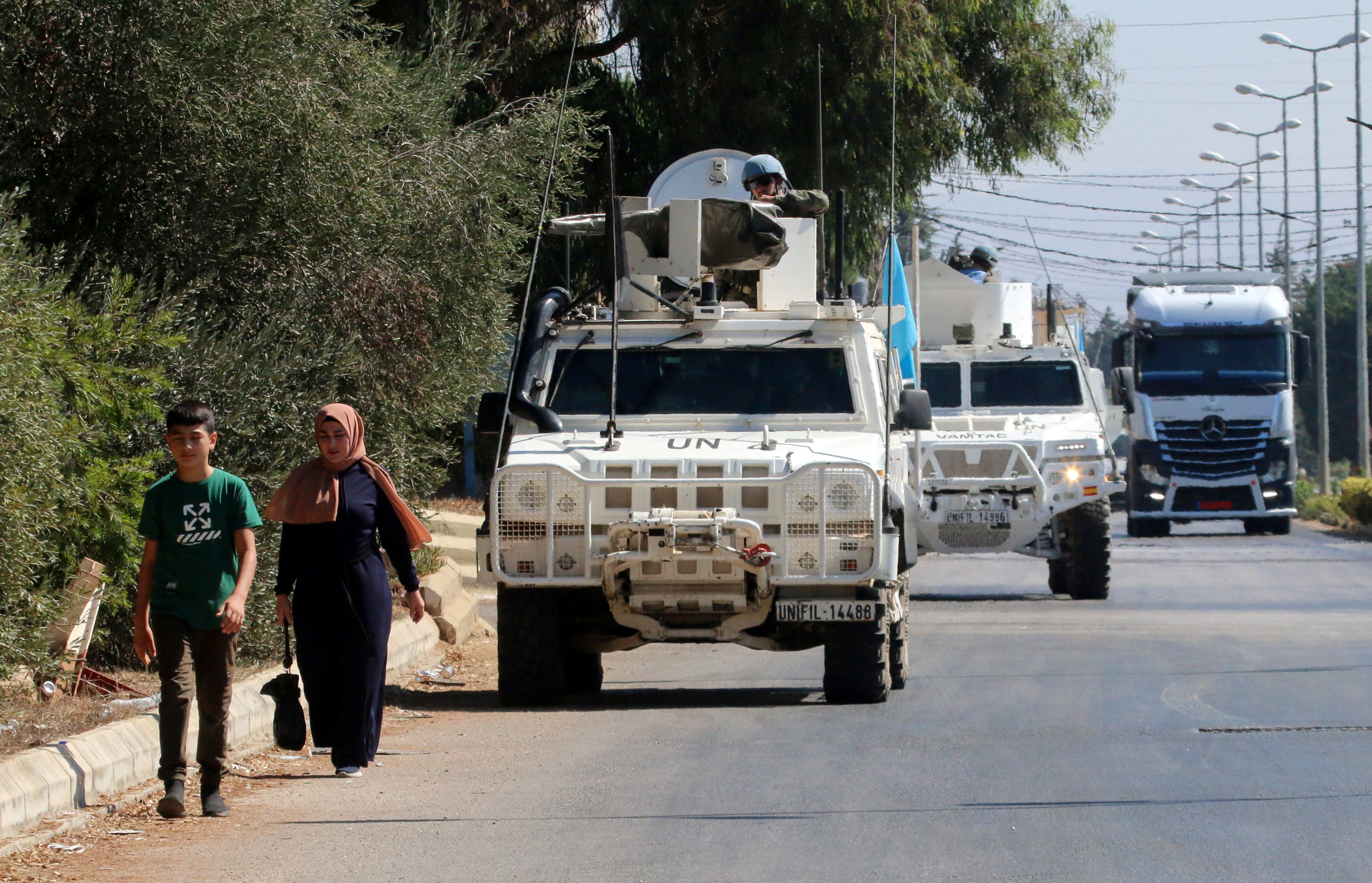 People walk near UN peacekeepers (UNIFIL) vehicles in Marjayoun, near the border with Israel, in southern Lebanon on August 9, 2024. Photo: Reuters