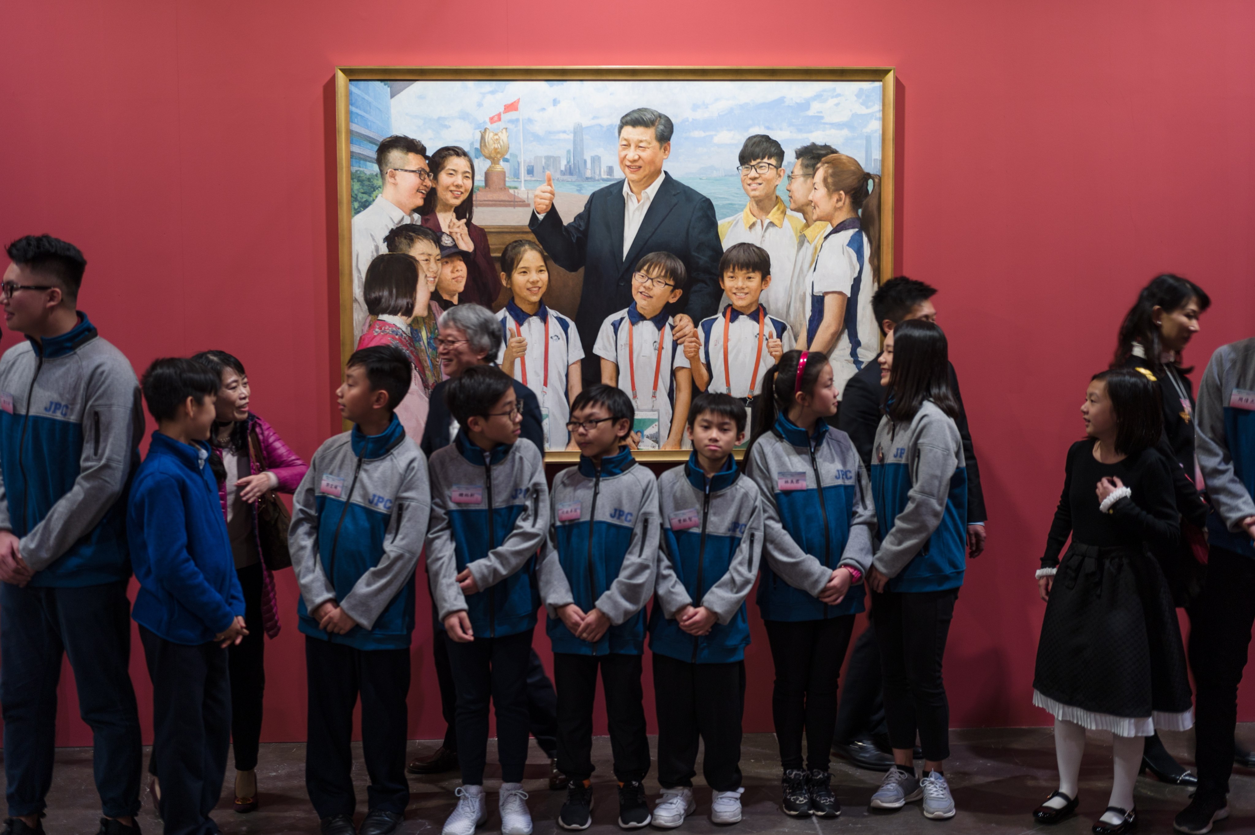 Children portrayed in a painting with Chinese President Xi Jinping stand next to the painting during the opening of the “HK Tugs at My Heartstrings” exhibition to mark 40 years of China’s reform and opening up policy on December 19, 2018. Photo: EPA-EFE