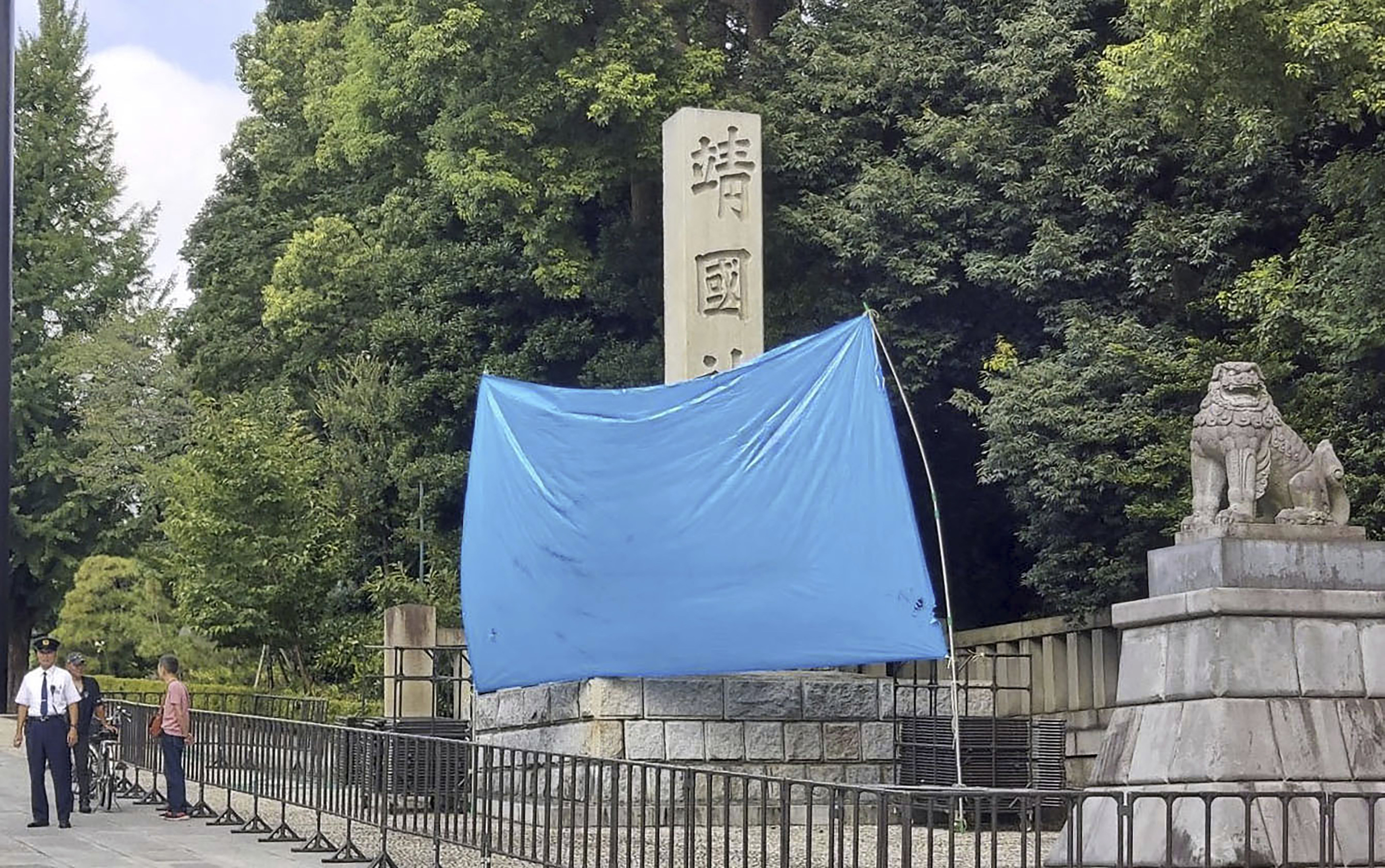 A blue sheet covers a stone pillar on which graffiti was found at Yasukuni Shrine in Tokyo on Monday. Photo: AP