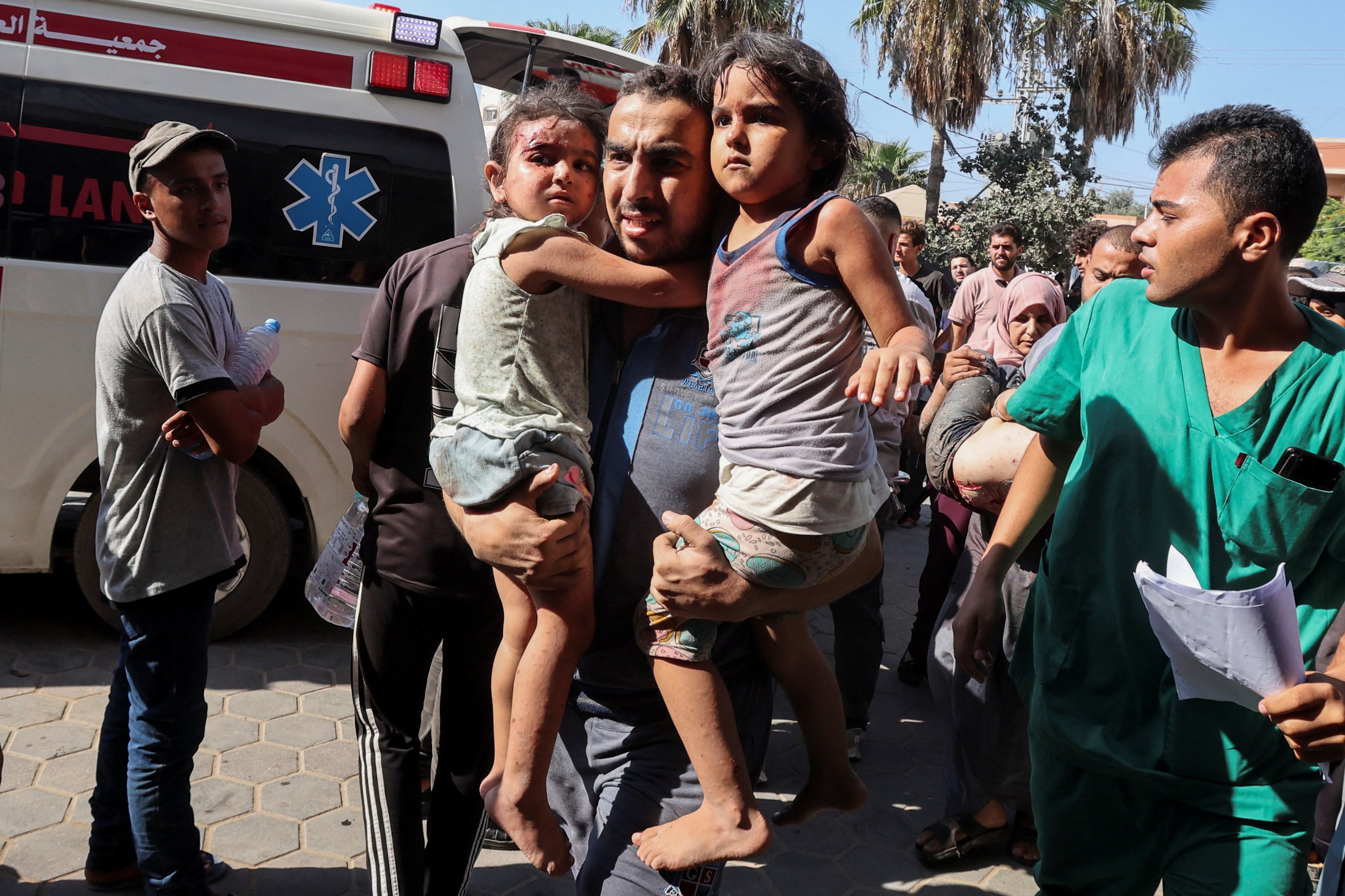 A Palestinian man carries children wounded in an Israeli strike at Al-Aqsa Martyrs Hospital in Deir al-Balah, central Gaza on Sunday. Photo: Reuters 