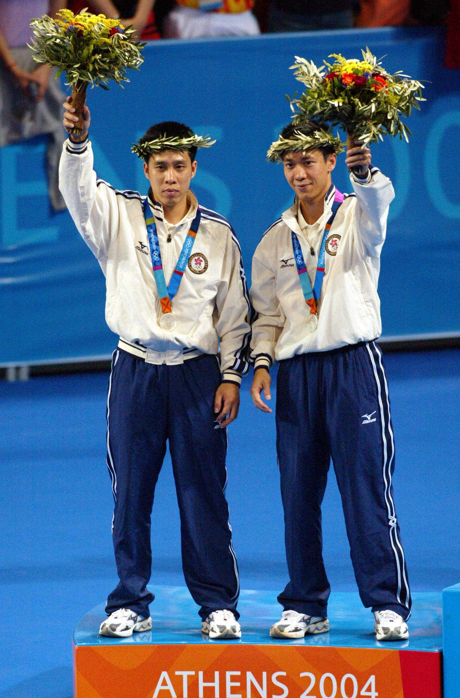 Silver medalists Ko Lai-chak and Li Ching of Hong Kong wave from the podium after the medal ceremony for the men’s doubles table tennis at the Athens Olympic Games on August 21, 2004. Photo: Reuters