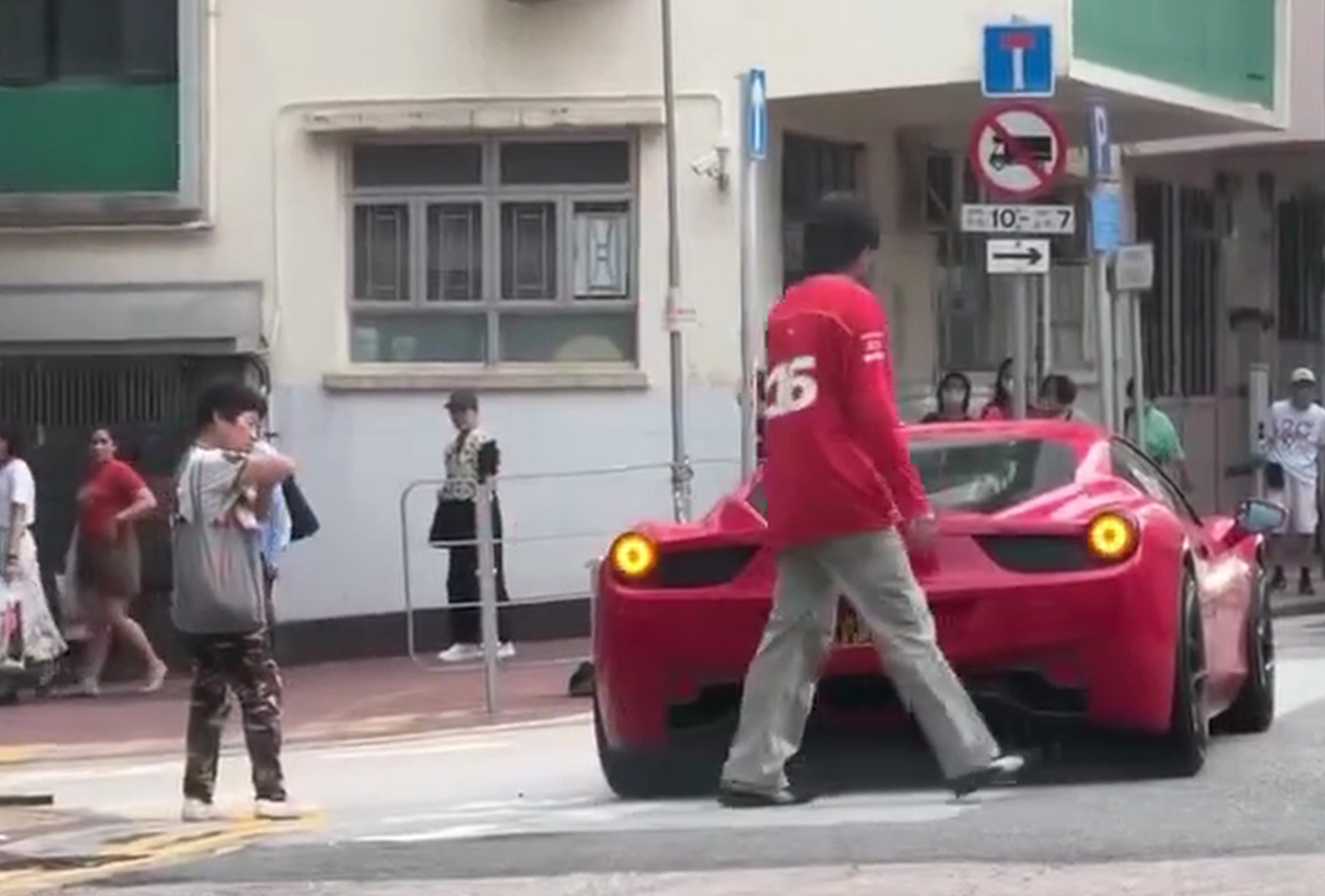 A screengrab shows singer Denis Kwok returning to his Ferrari after speaking to a pedestrian.who checks her elbow.
Photo: SCMP