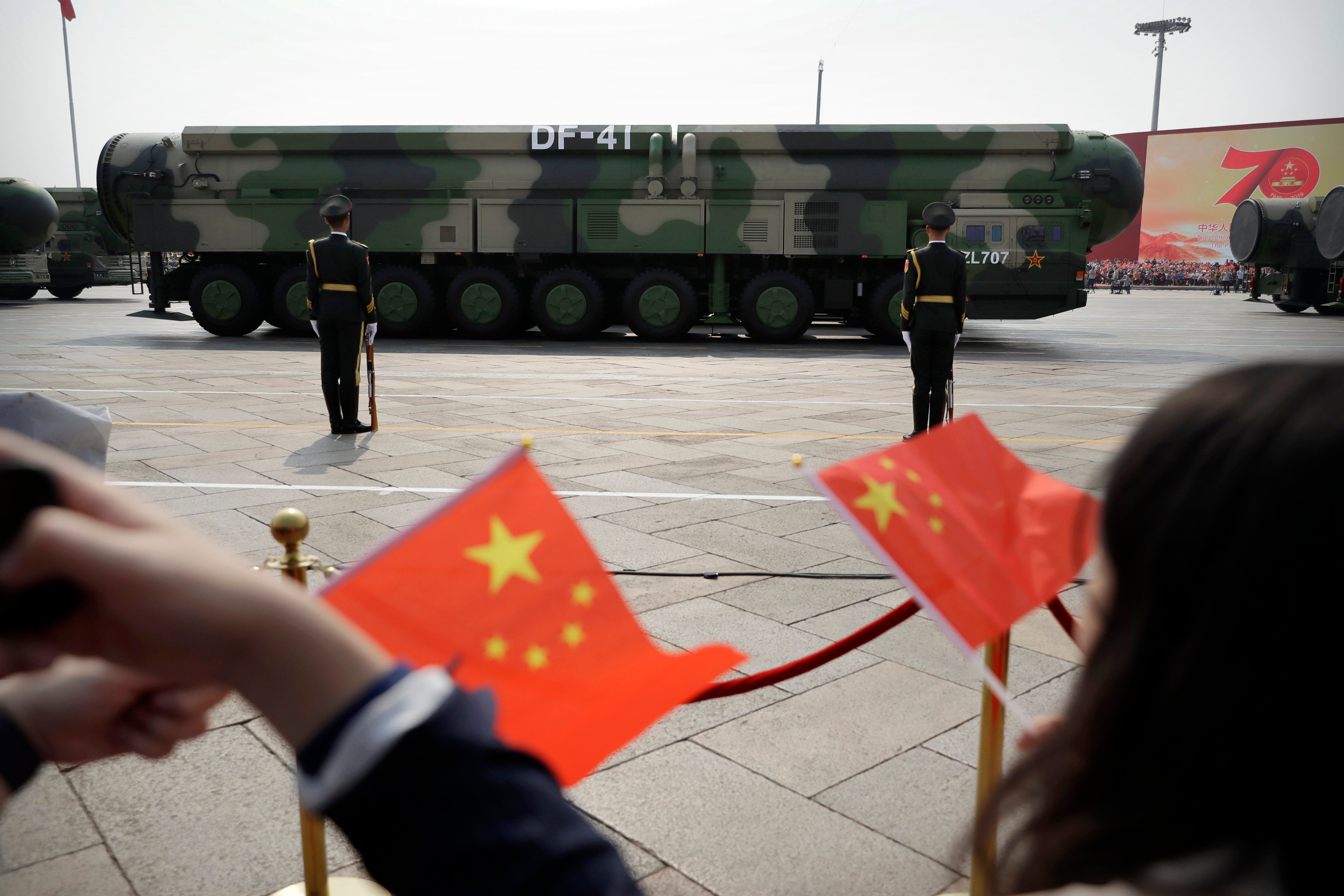 Spectators wave Chinese flags as military vehicles carrying DF-41 ballistic missiles roll during a parade in Beijing in October 2019. Photo: AP