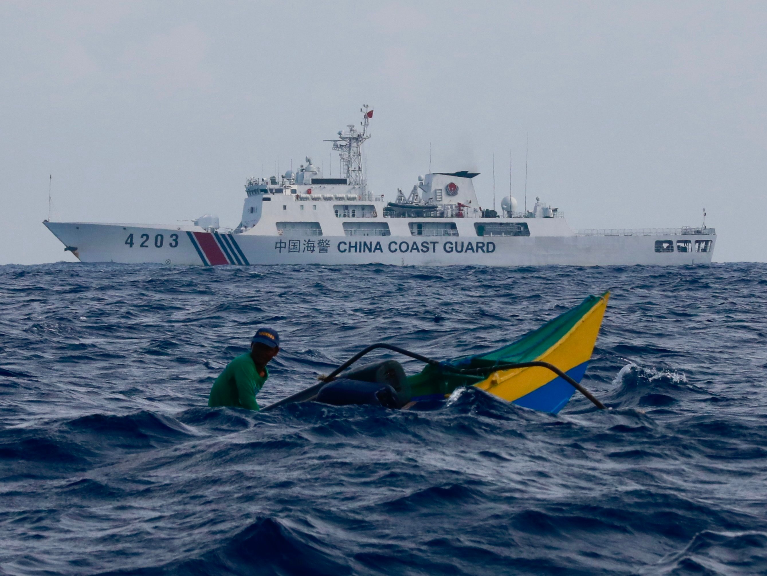 A China Coast Guard patrol ship manoeuvres near a Filipino fisherman aboard a motorised wooden boat sailing towards Scarborough Shoal in the disputed South China Sea in May. Photo: EPA-EFE