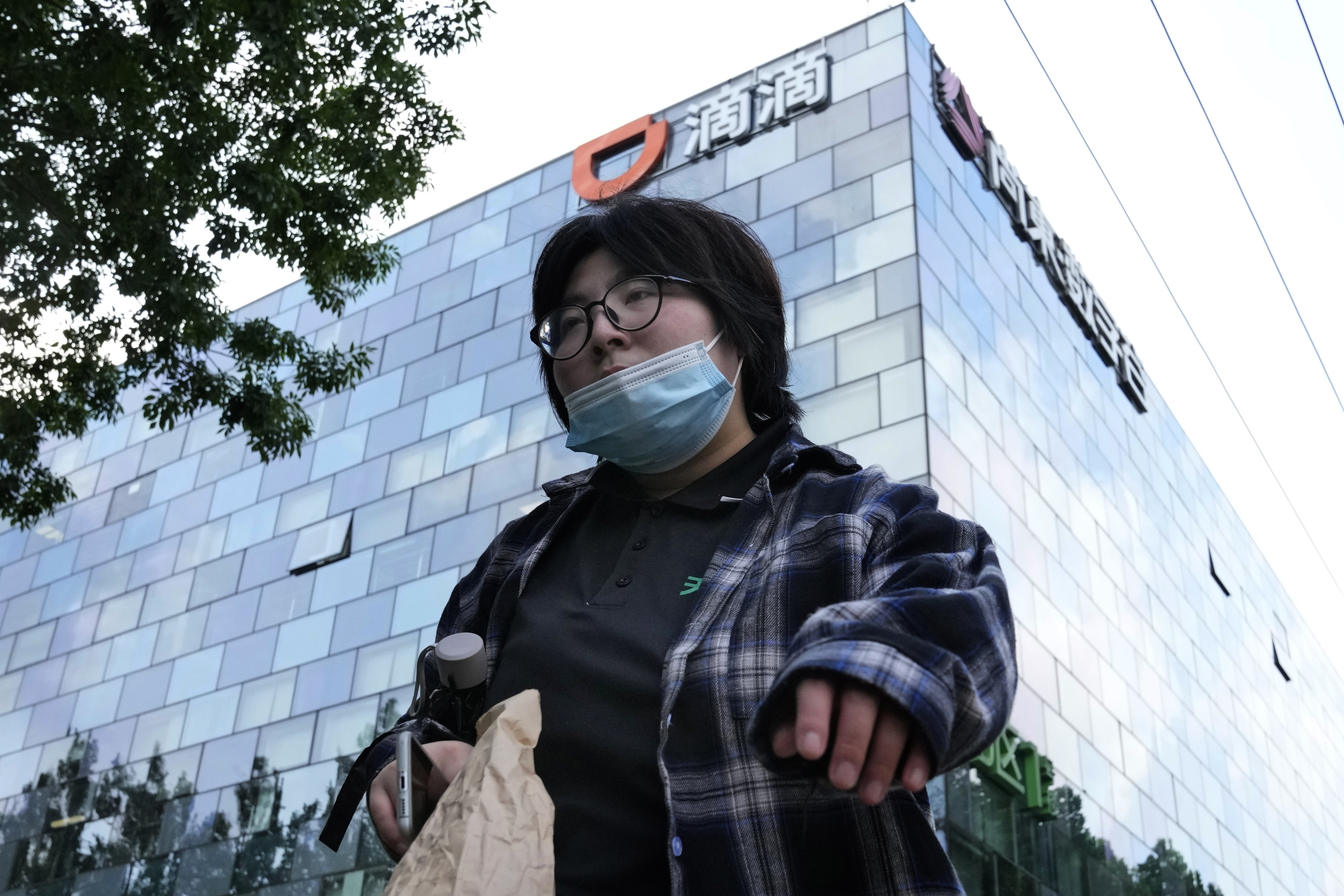 A woman walks past the headquarters of Didi Global in Beijing. Photo: AP