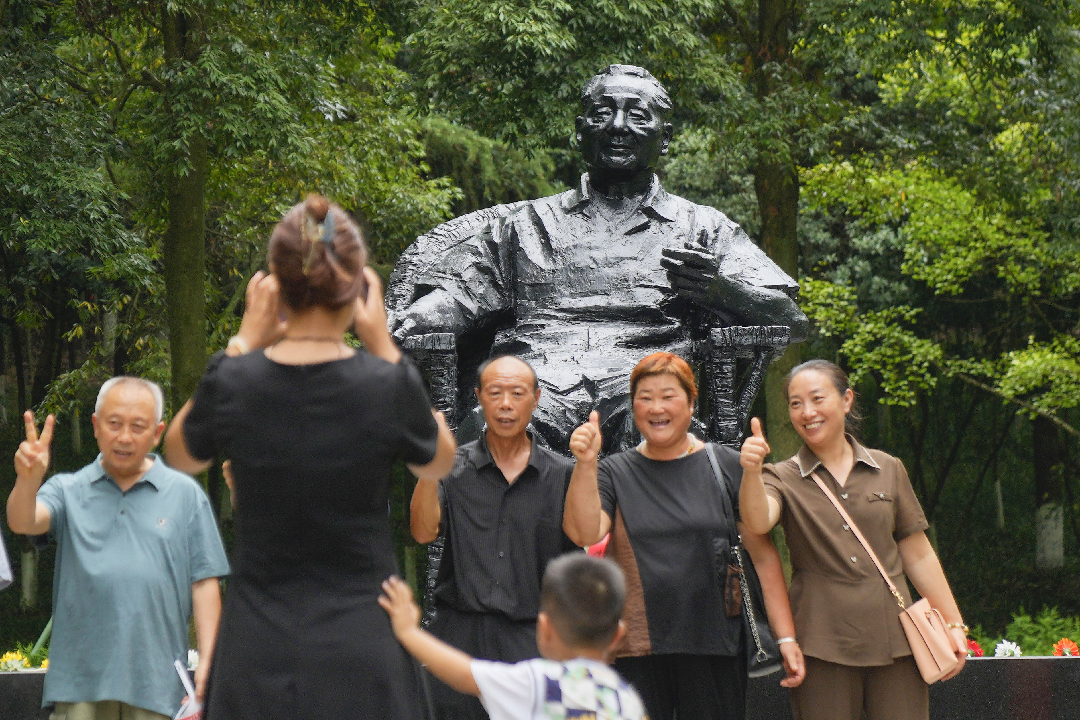 Tourists pose for a photo in front of a bronze statue of the late Chinese leader Deng Xiaoping near his birthplace in Guangan, Sichuan province, on August 14. Photo: Kyodo