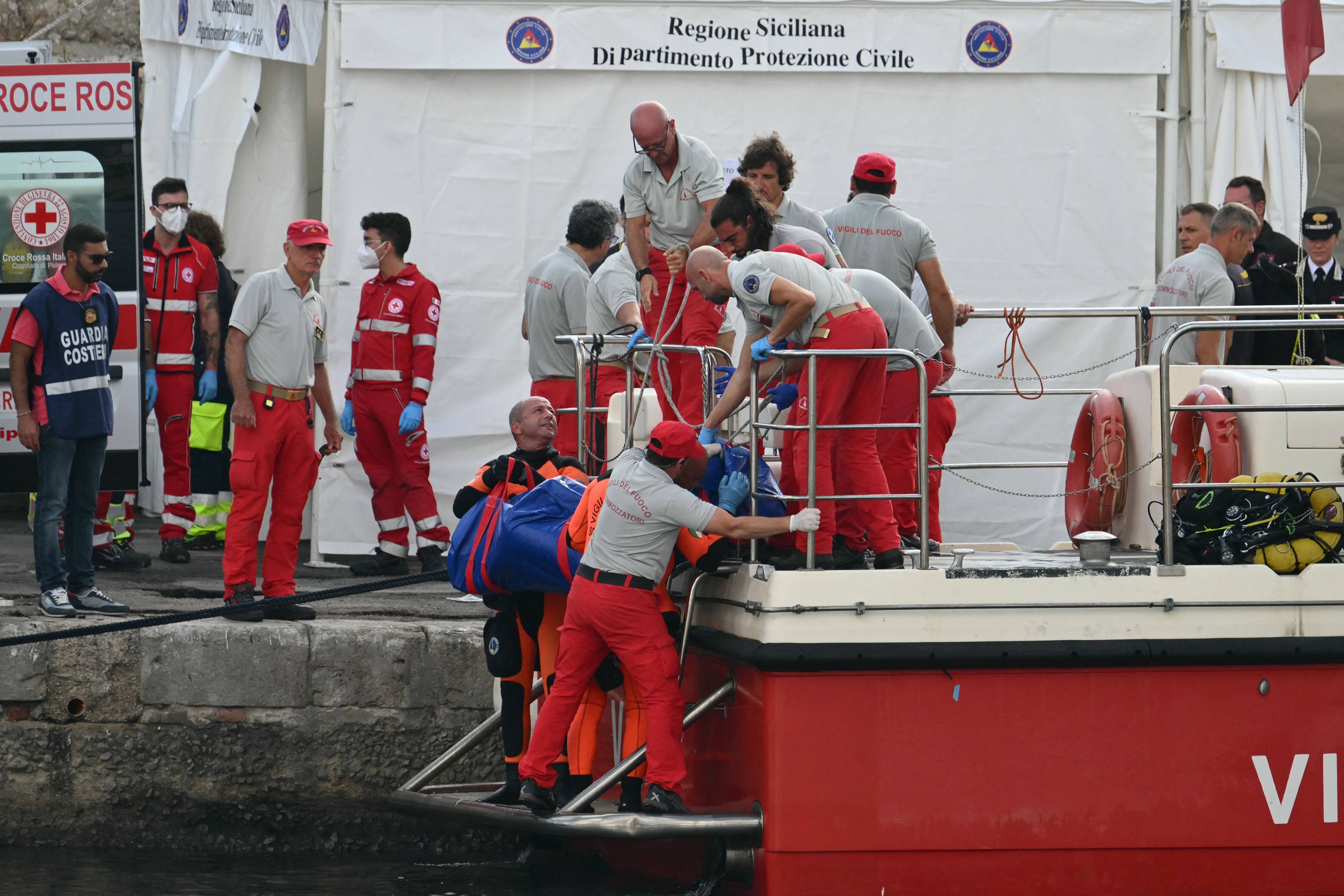 Rescuers carry a body after divers return in Porticello harbour. Photo: AFP