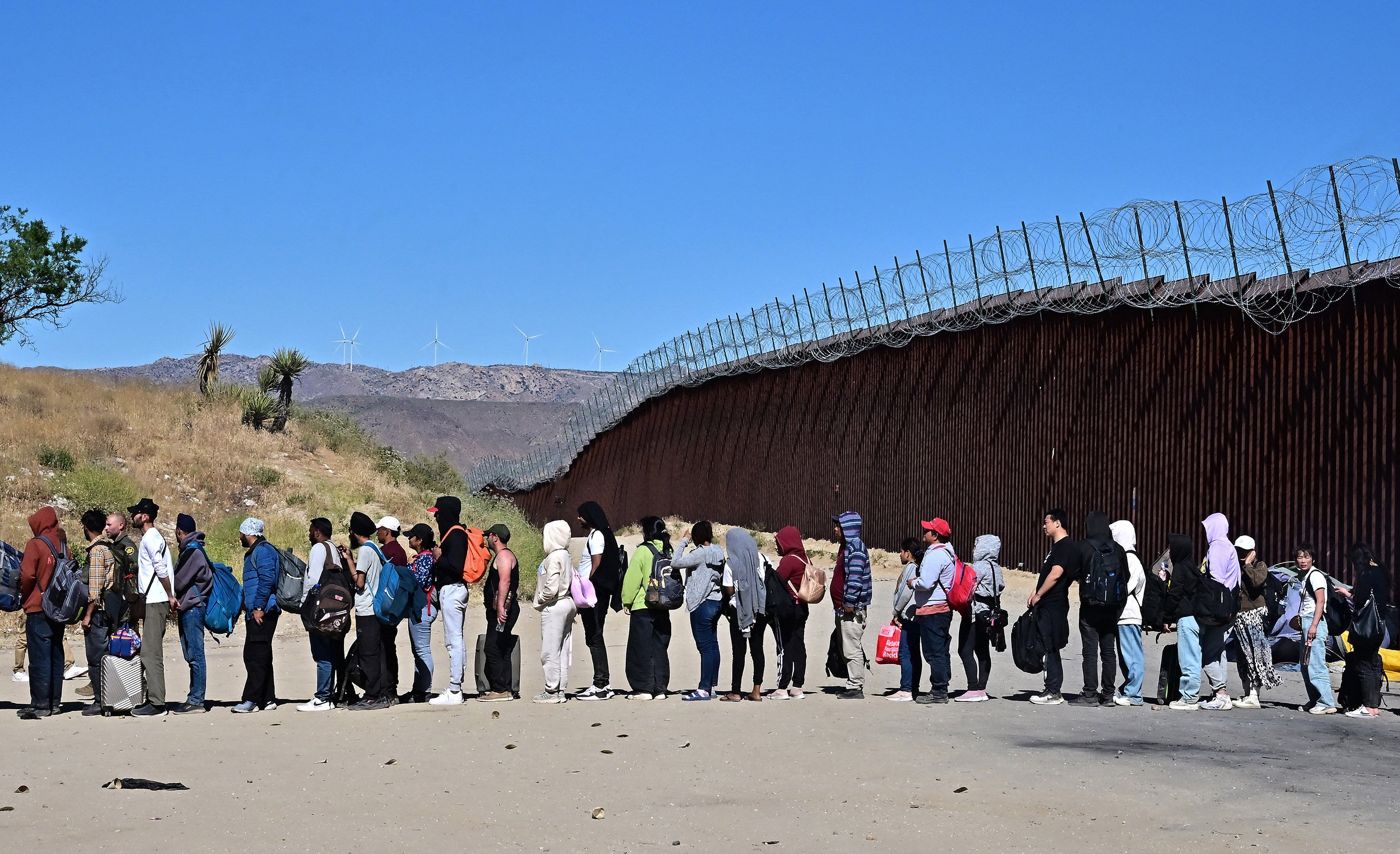 Migrants wait in line hoping for processing from US Customs and Border Patrol agents after arriving in California from Mexico. Photo: AFP/Getty Images/TNS