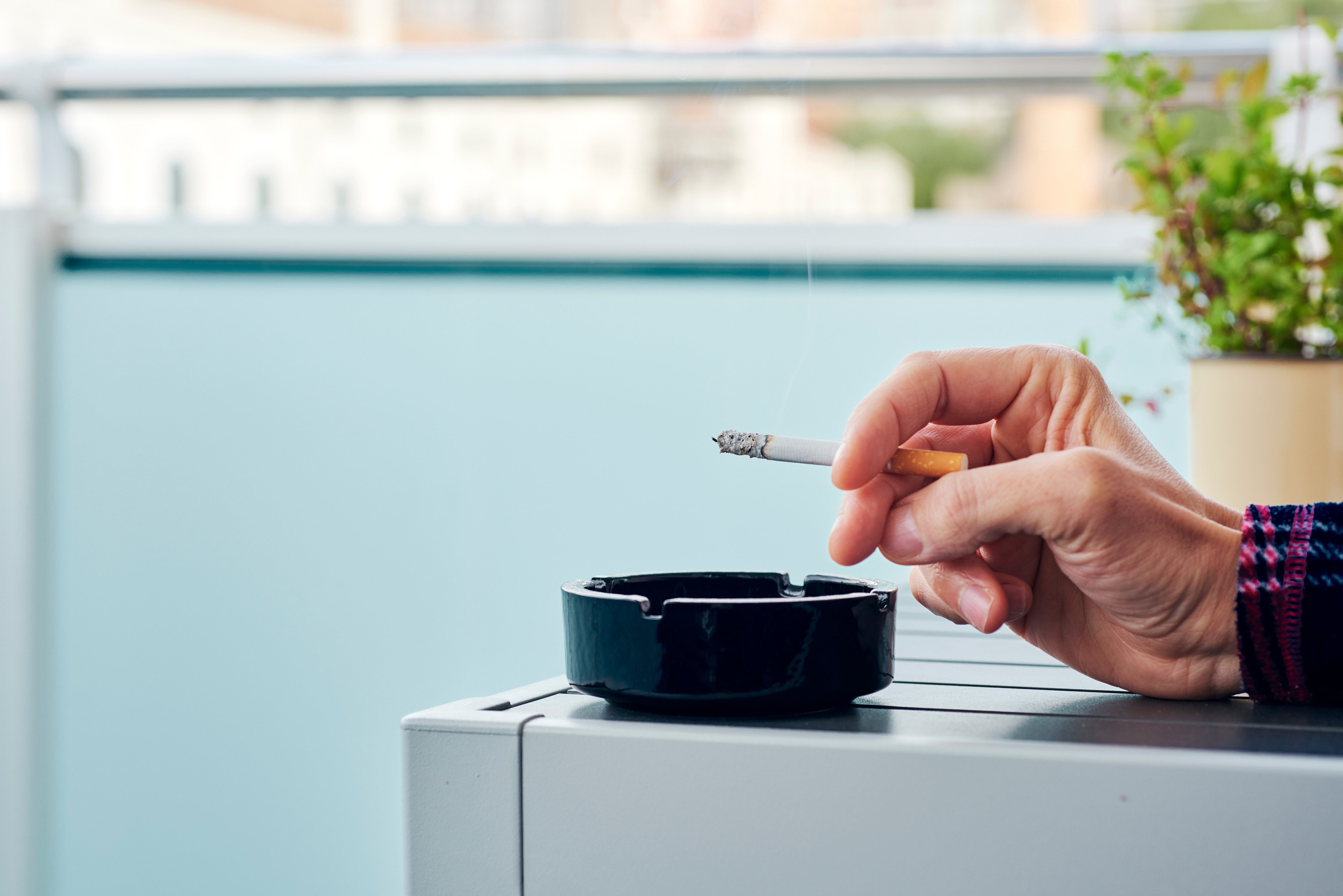 A man smokes a cigarette at home. Photo: Shutterstock