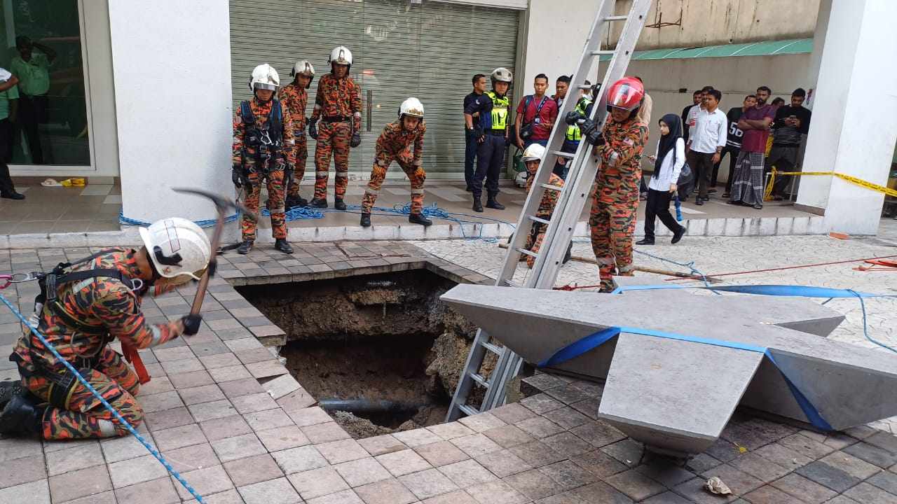 Crews work to rescue a woman who fell into a sinkhole on a busy Kuala Lumpur street. Photo:  Kuala Lumpur Fire and Rescue Department