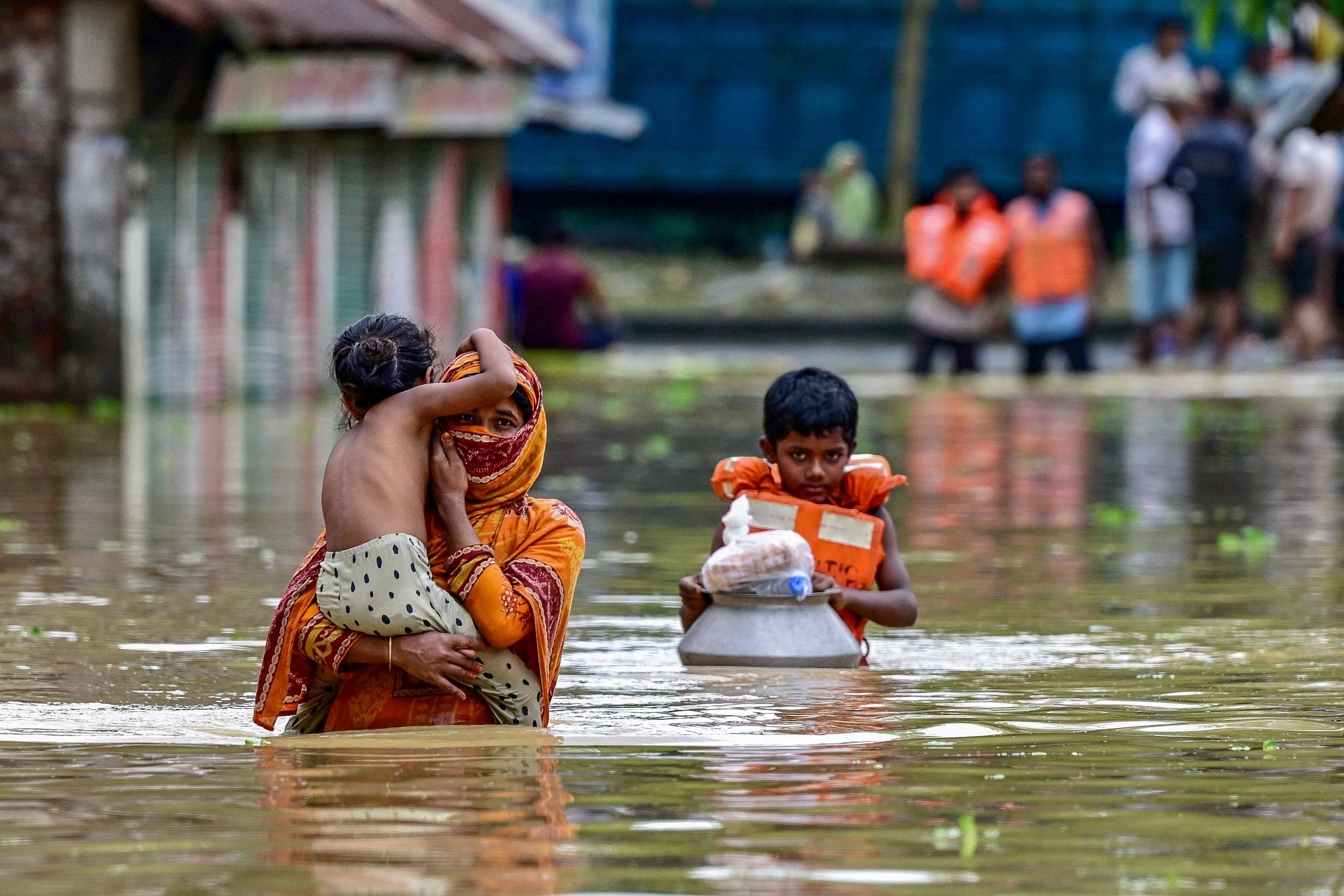 People wade through flood waters after collecting relief materials in Feni, in south-eastern Bangladesh, on August 24, 2024. Photo: AFP