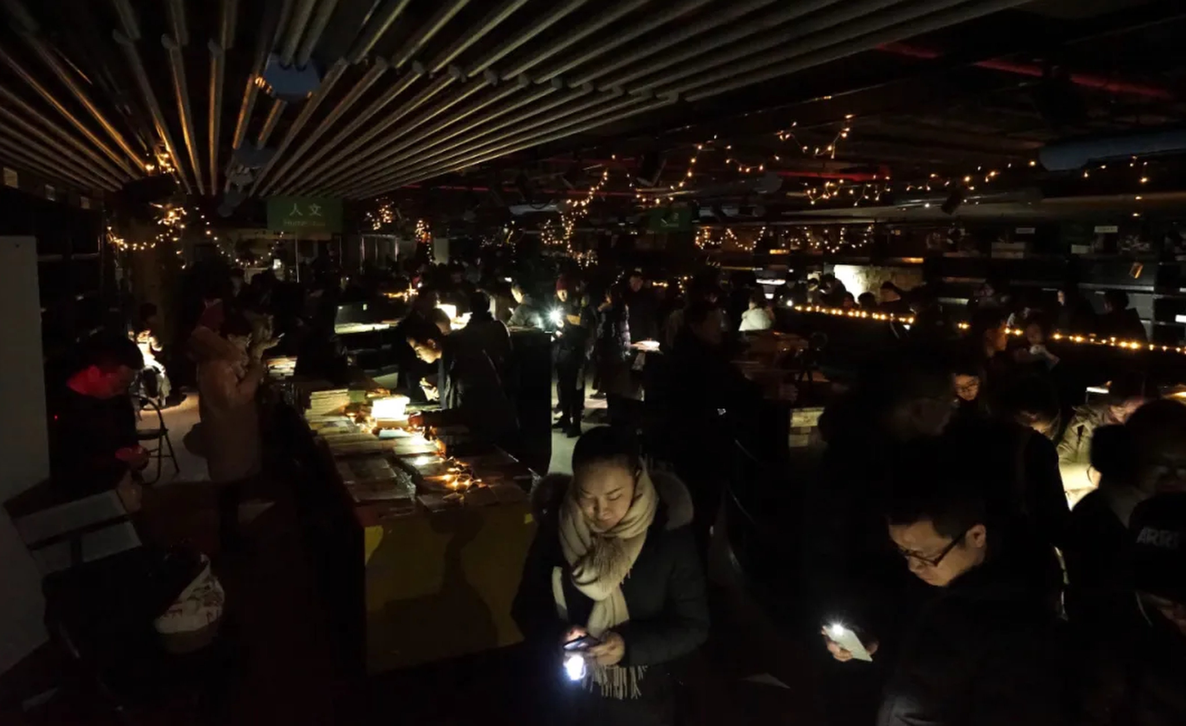 Fans of Shanghai Jifeng Bookstore’s last branch browse under mobile phone torches after the power supply is cut off pending lease expiry, in January 2018. Photo: WeChat/ 季风微读圈