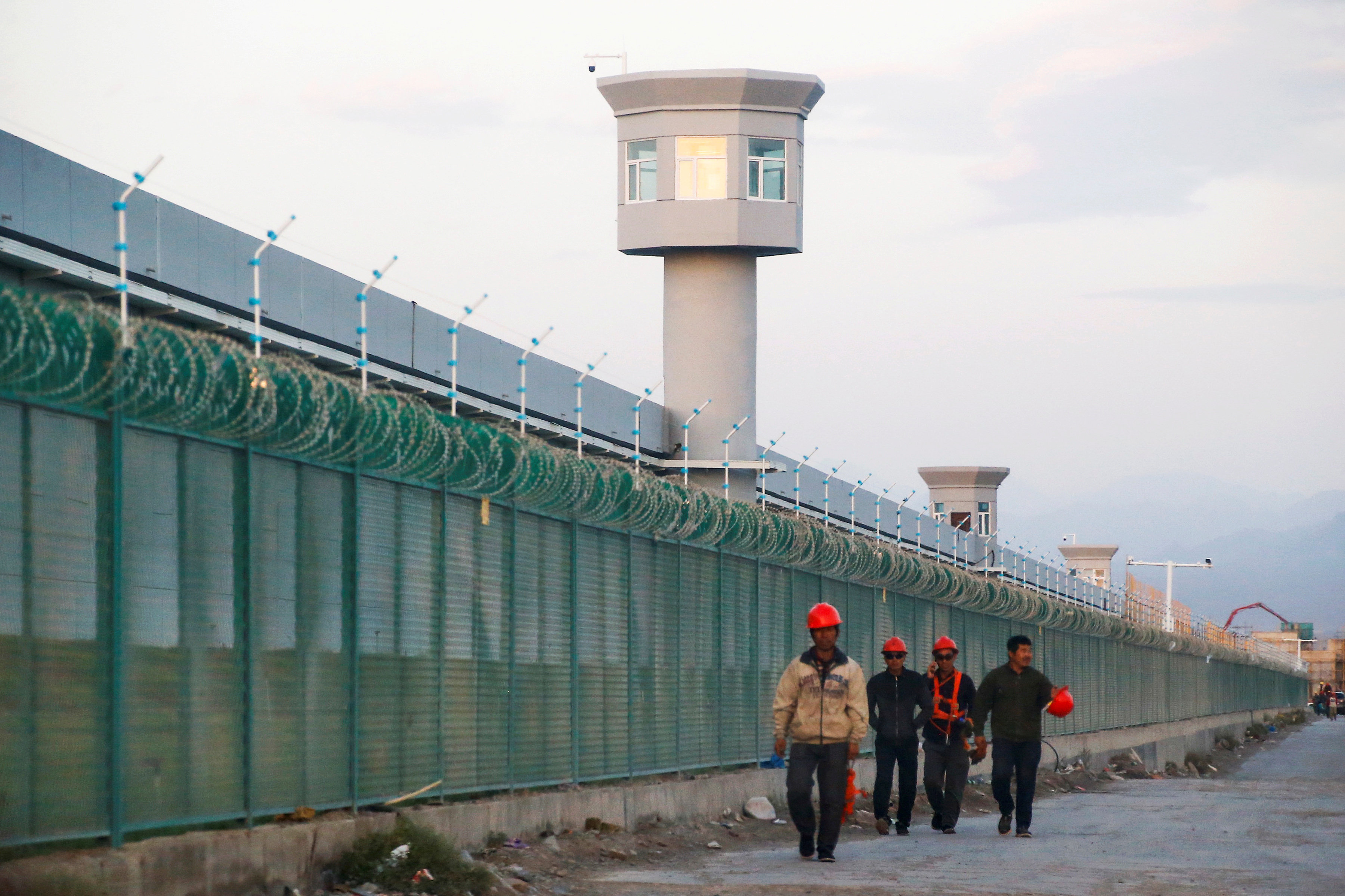 Workers walk along a perimeter fence of what Chinese officials call a vocational skills education centre in Dabancheng in Xinjiang. Photo: Reuters