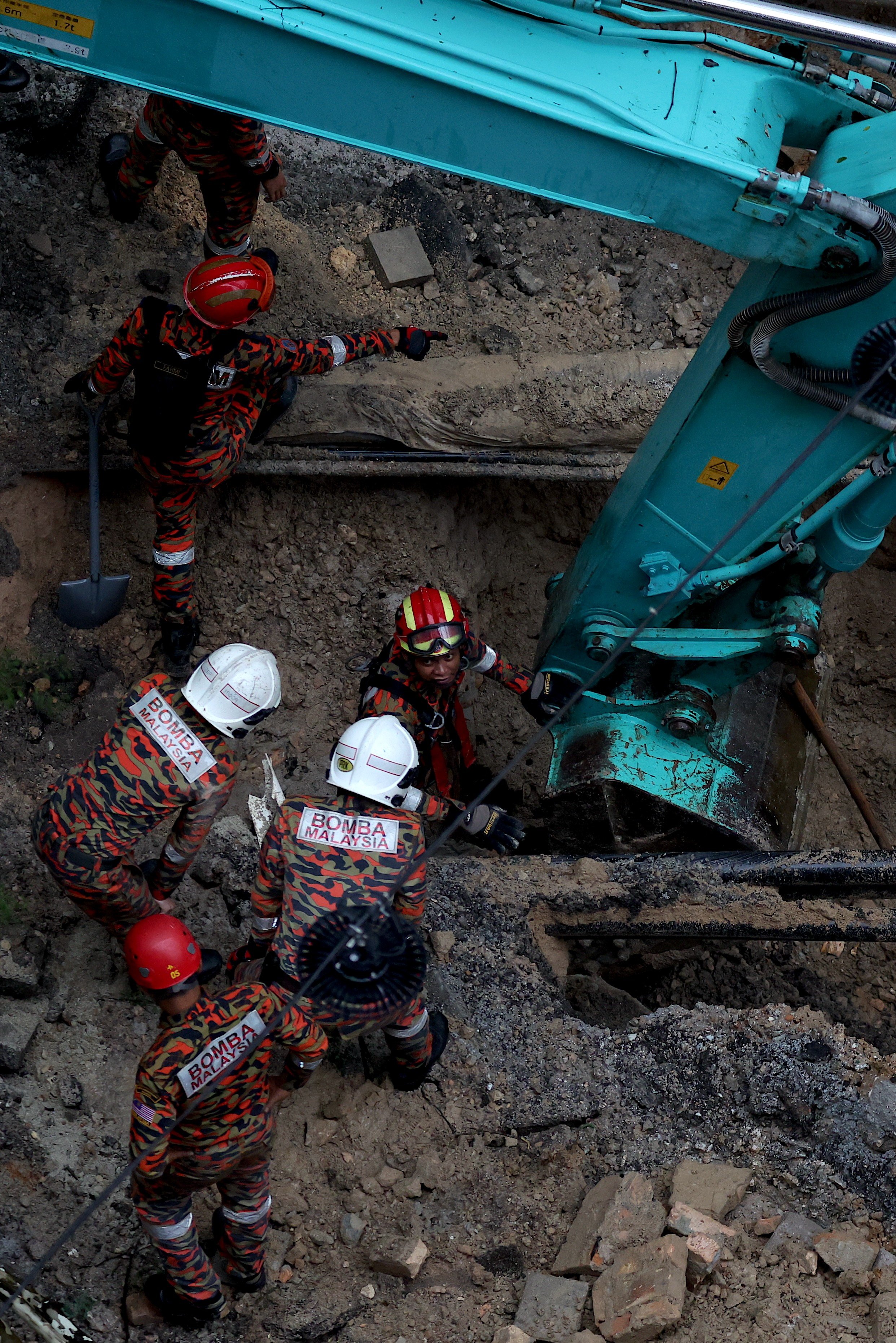 Malaysian rescuers inspect the site where a woman fell into an eight-meter deep sinkhole in Kuala Lumpur on Friday. Photo: EPA-EFE