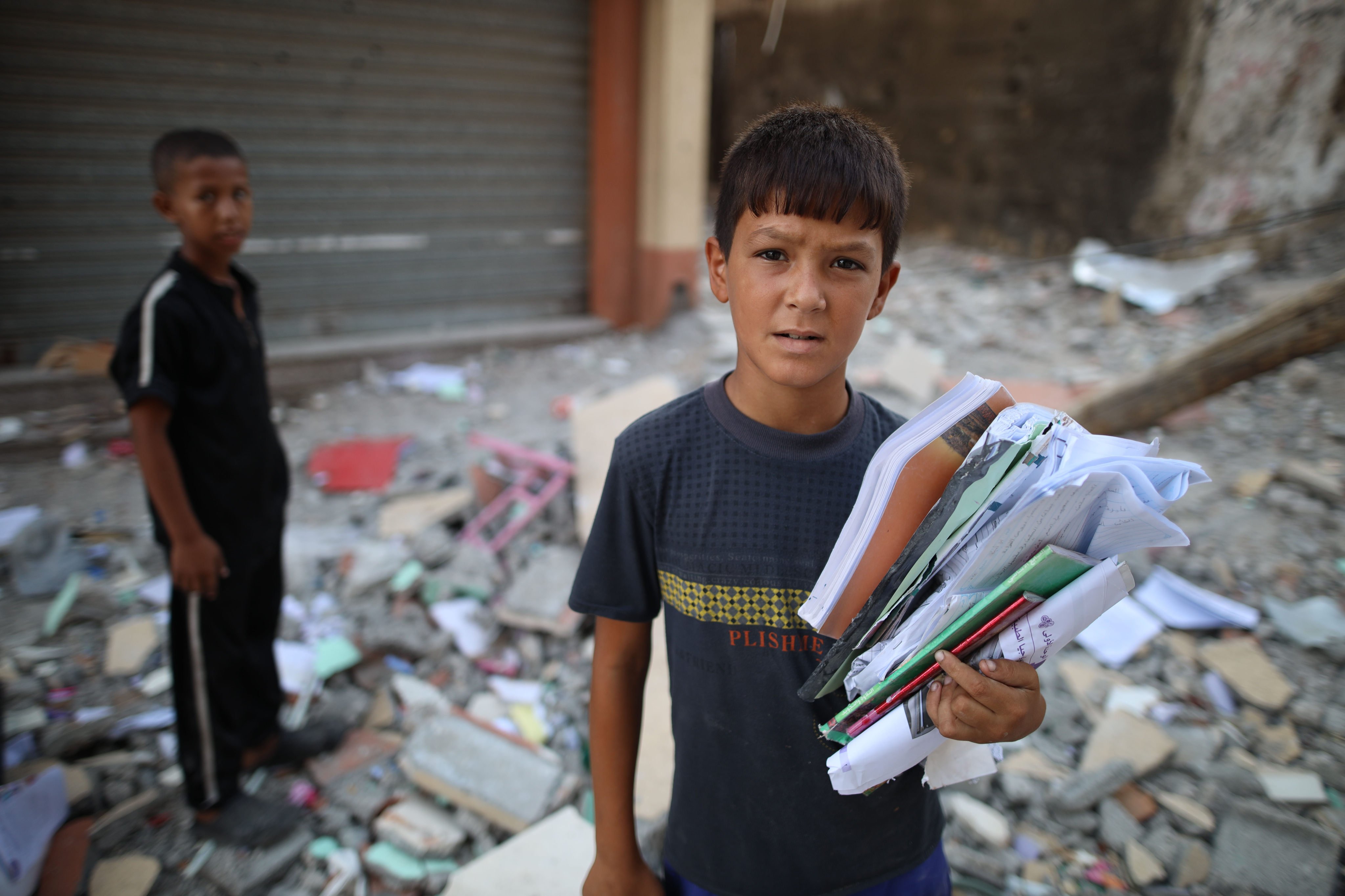 Palestinian children collect belongings from a building targeted in an Israeli airstrike in central Gaza’s Maghazi refugee camp on Tuesday. Photo: Xinhua