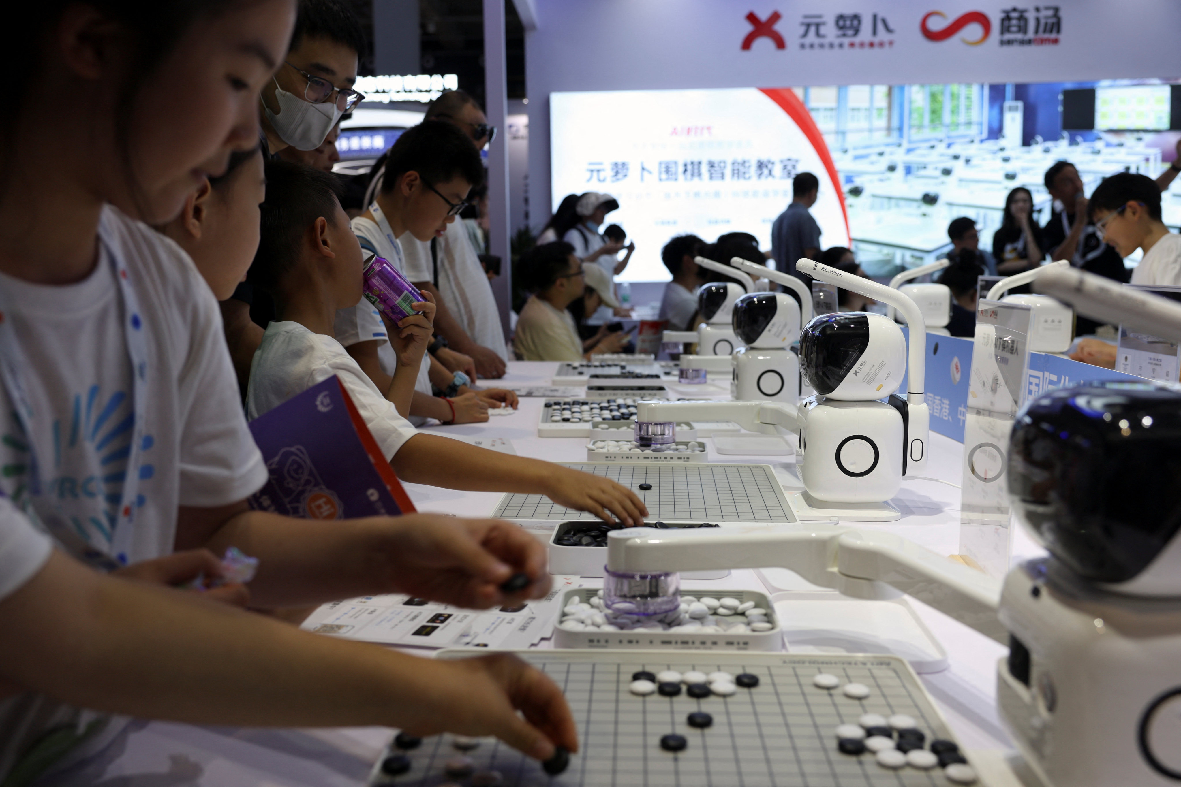 Visitors play Go against SenseRobots displayed at the SenseTime booth during the World Robot Conference in Beijing on August 21, 2024. Photo: Reuters