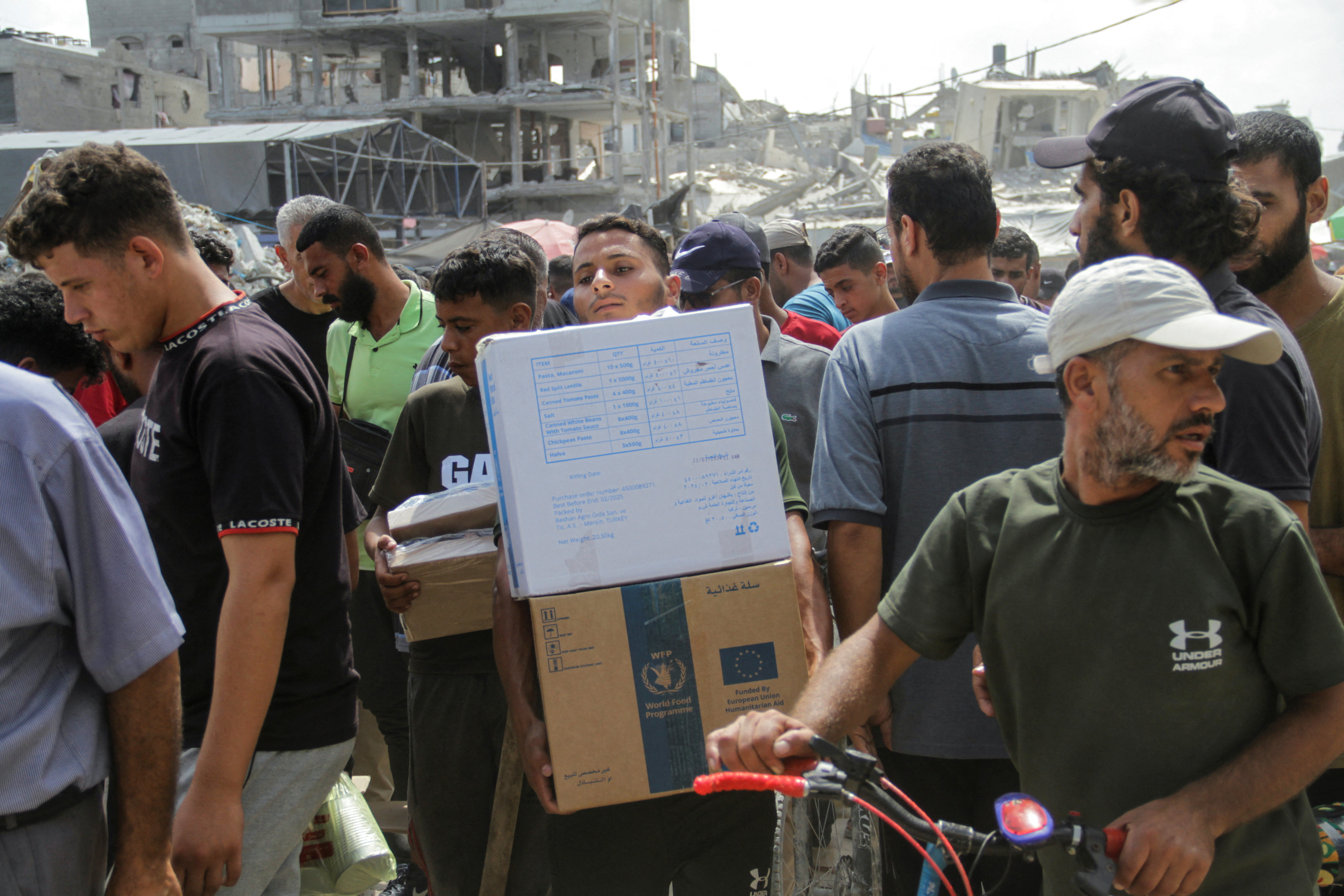 A man carries boxes as Palestinians gather to receive aid, including food provided by the World Food Programme (WFP), outside a UN distribution centre in Jabilia, northern Gaza. Photo: Reuters