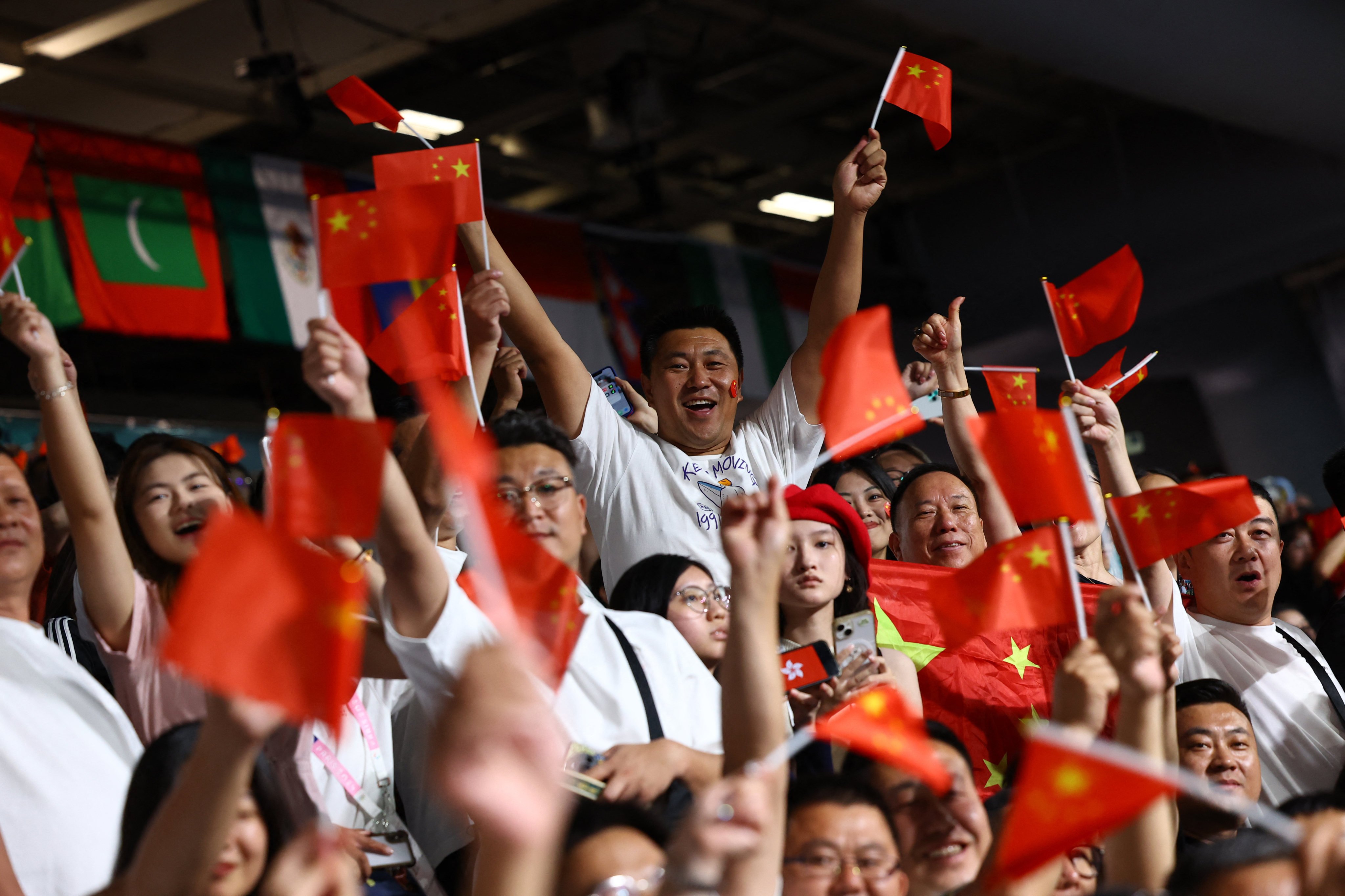 Fans wave China flags as the Hong Kong flag is displayed on a phone, before the table tennis mixed doubles semi-final between Hong Kong and North Korea at the Paris Olympics on July 29. Photo: Reuters