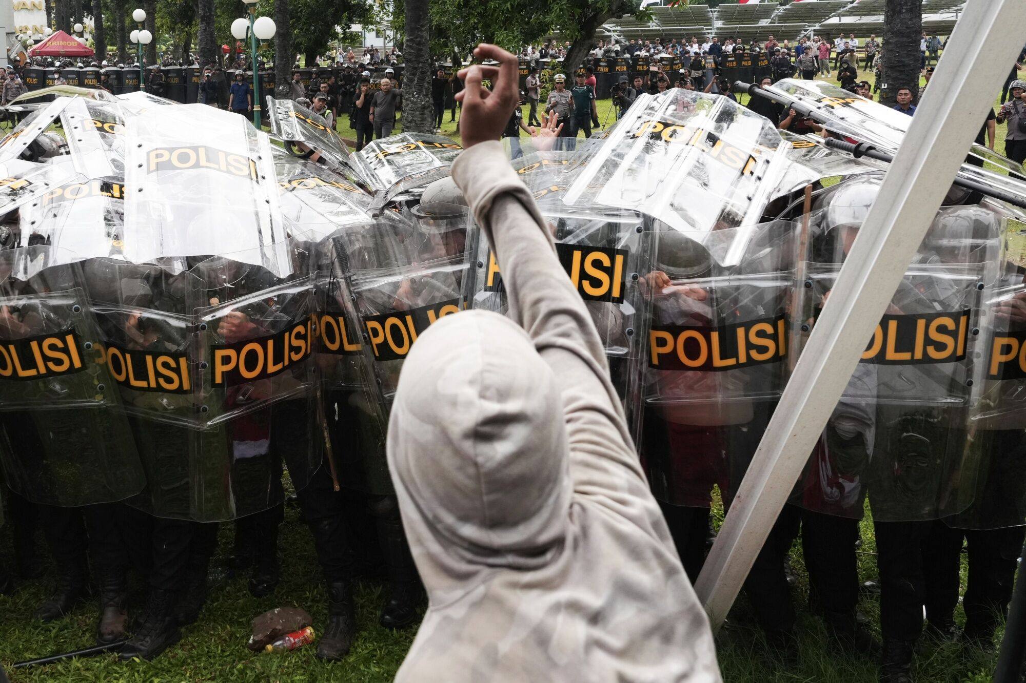 A protester throws a rock at police officers outside the parliament in Jakarta. Photo: Bloomberg