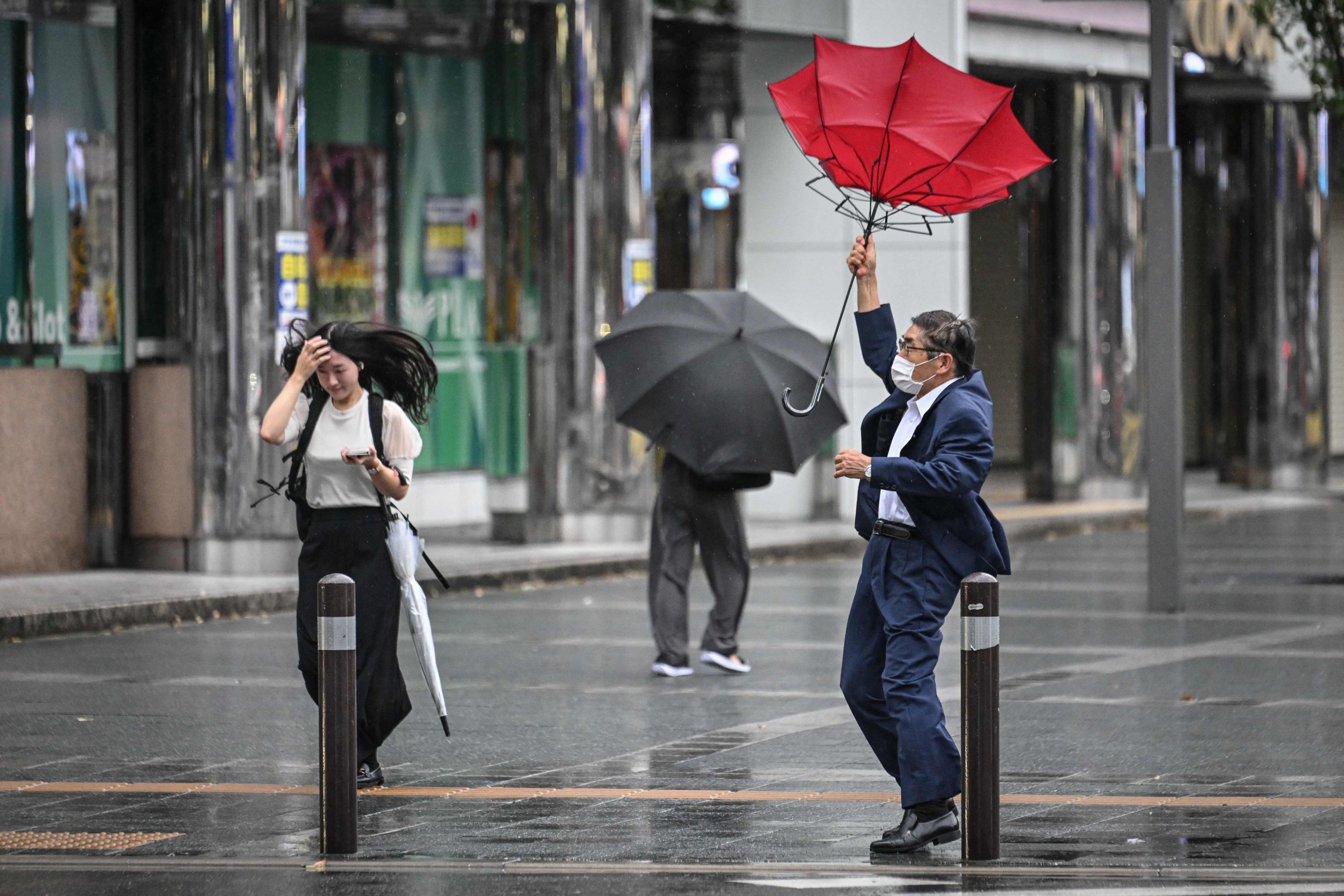 A man holds his umbrella in the wind outside Hakata station in Fukuoka, Japan, on Thursday. Photo: AFP