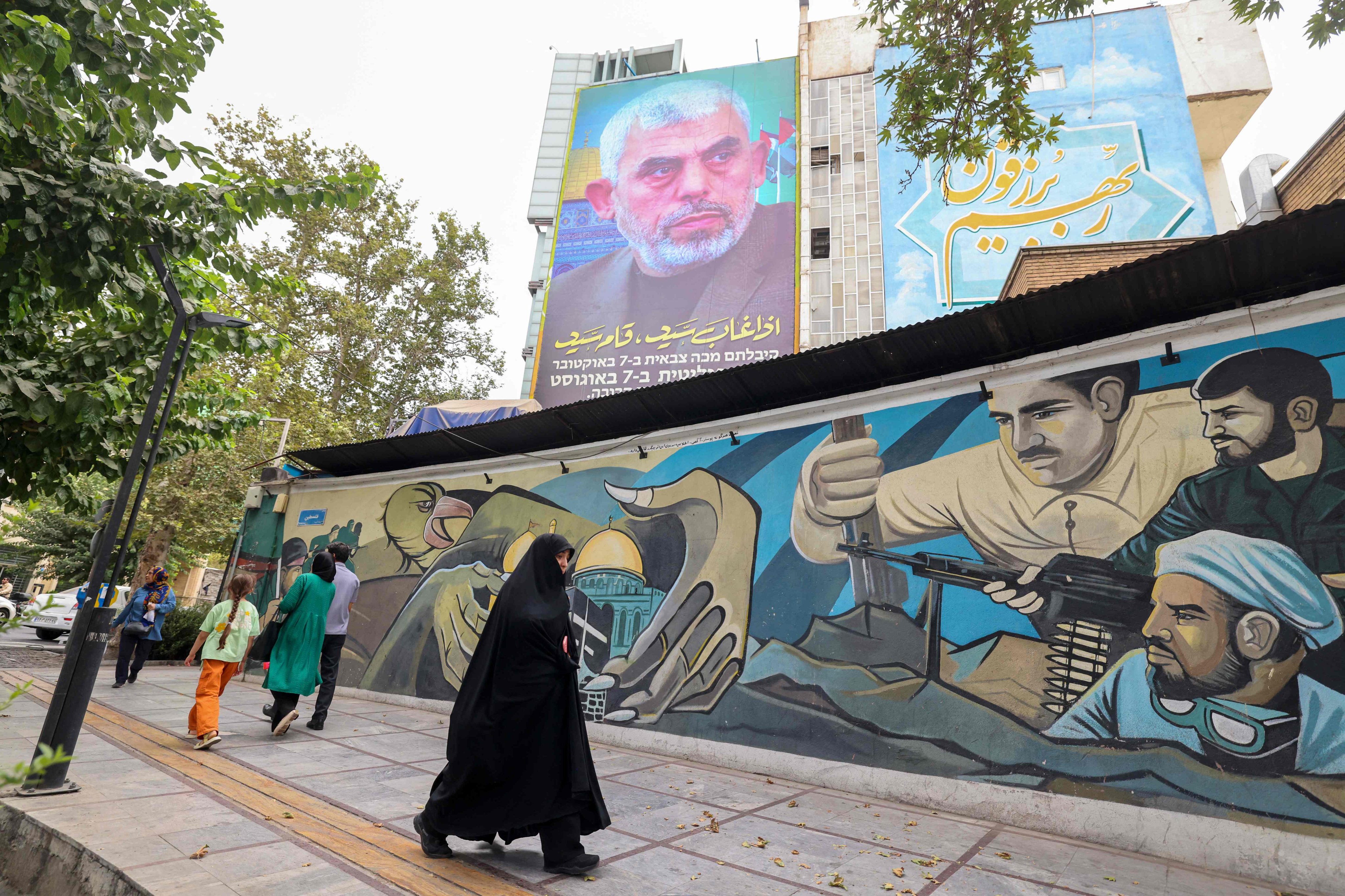 People walk past a billboard showing a portrait of newly appointed Hamas leader Yahya Sinwar next to Palestine Square in the Tehran on August 12. Photo: AFP