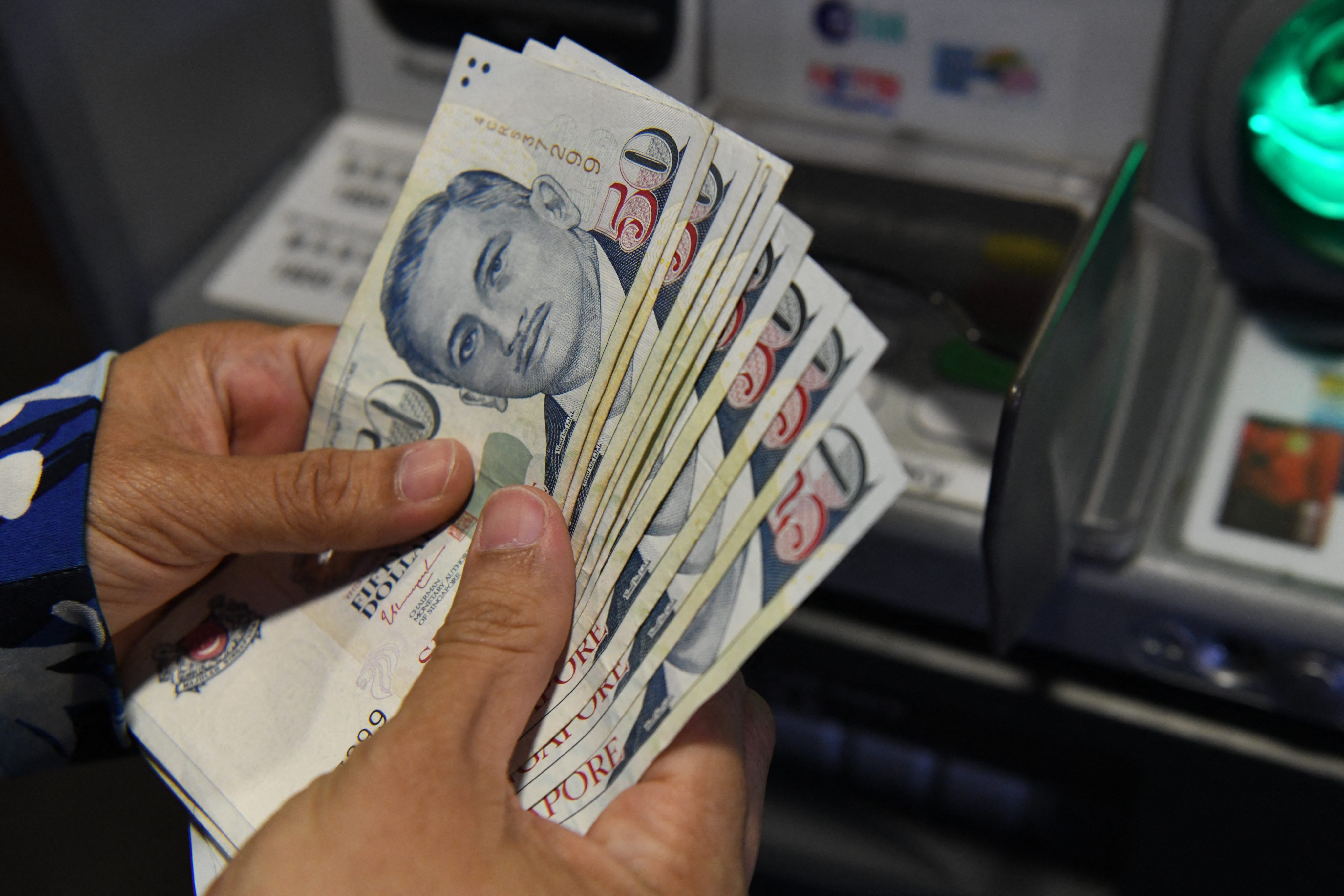 A customer withdraws Singapore dollar notes. Photo: AFP