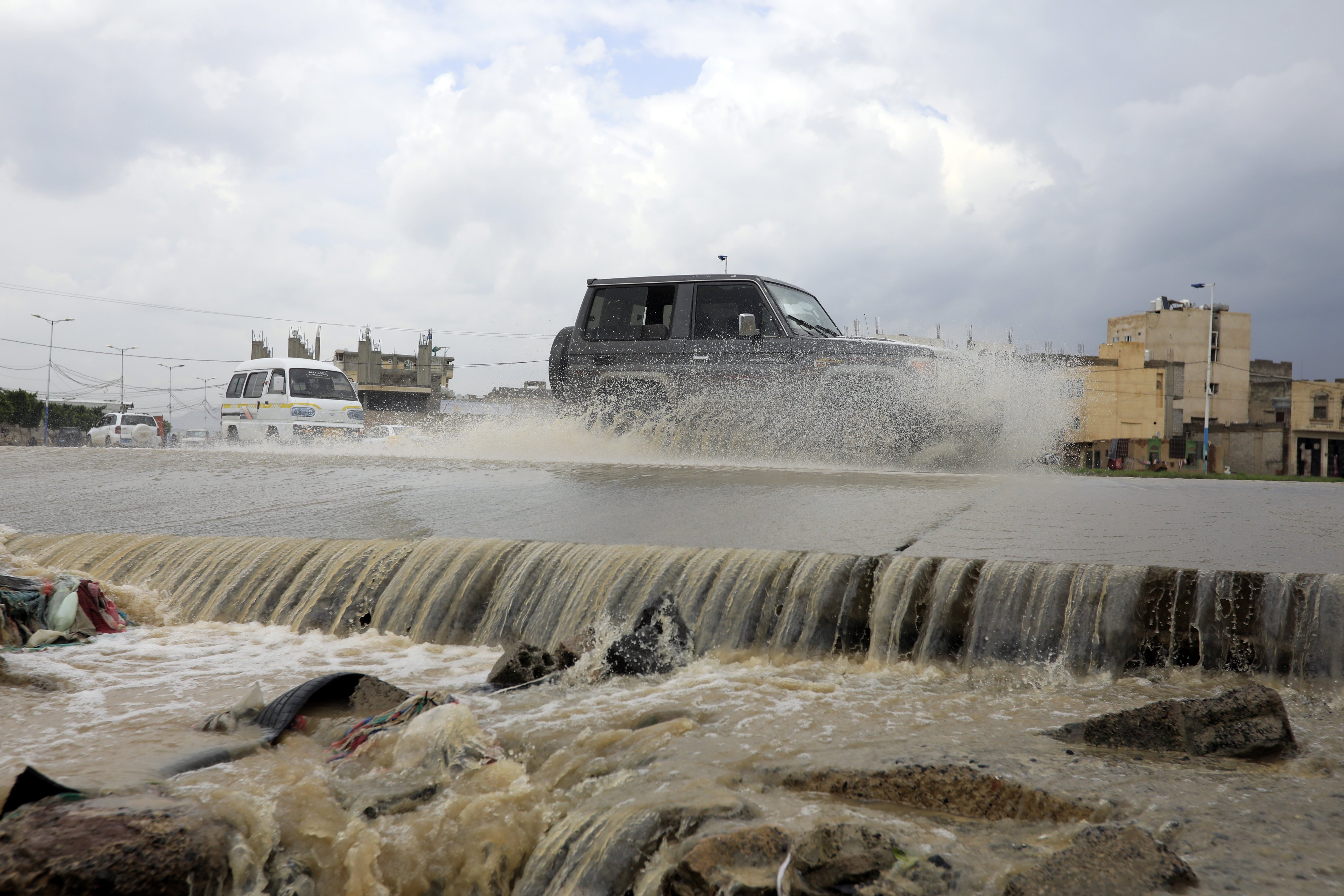 Vehicles drive through a flooded stream caused by heavy rains in Sana’a, Yemen, on Wednesday. At least 33 people have died and 28 homes were destroyed after a dam collapsed in the province of Al-Mahweet after heavy rains and floods. Photo: EPA-EFE