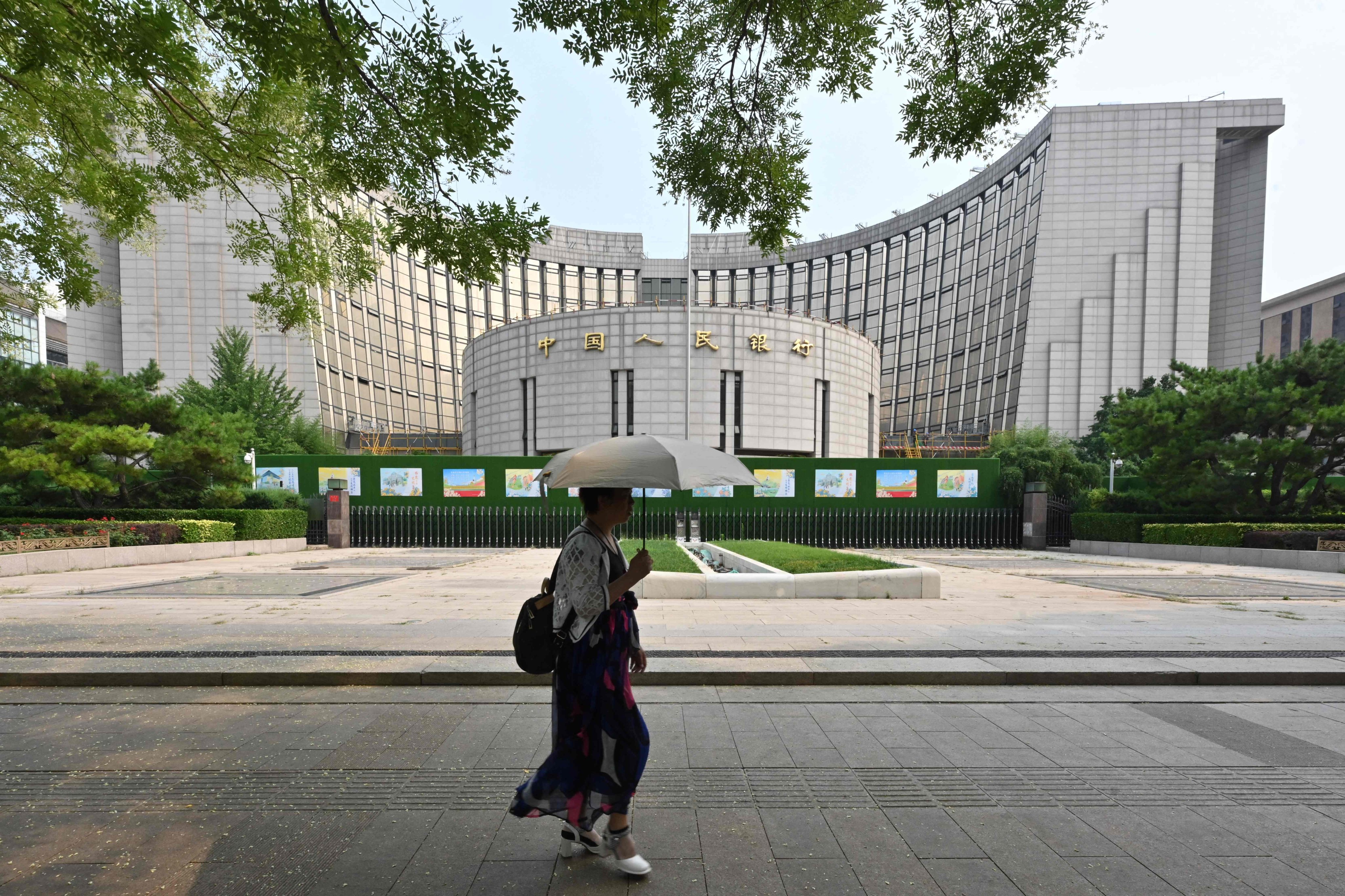 A woman walks past the headquarters of the People’s Bank of China. Photo: AFP