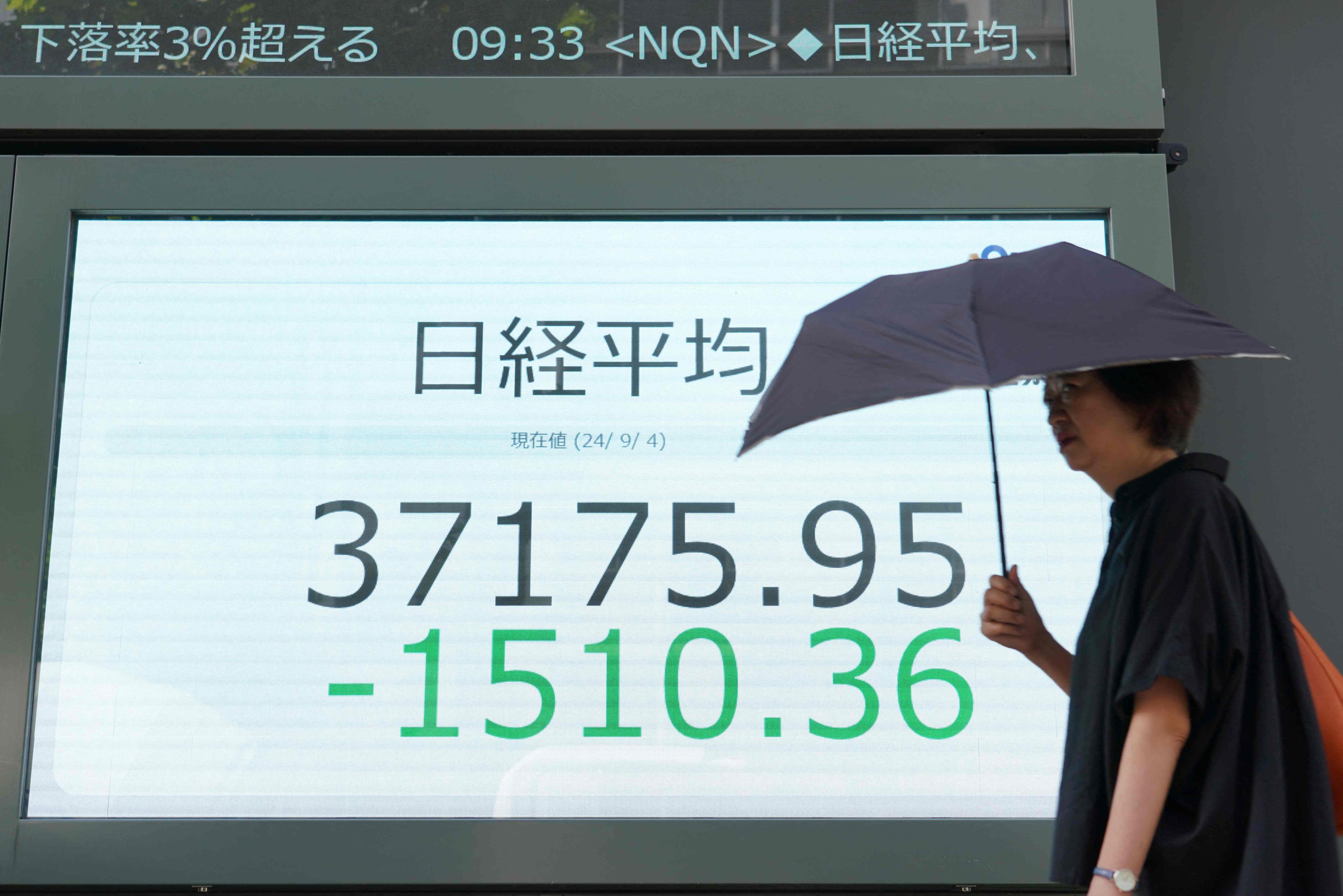 A woman walks in front of a screen board displaying share prices on the Tokyo Stock Exchange in Tokyo on September 4, 2024. Photo: AFP